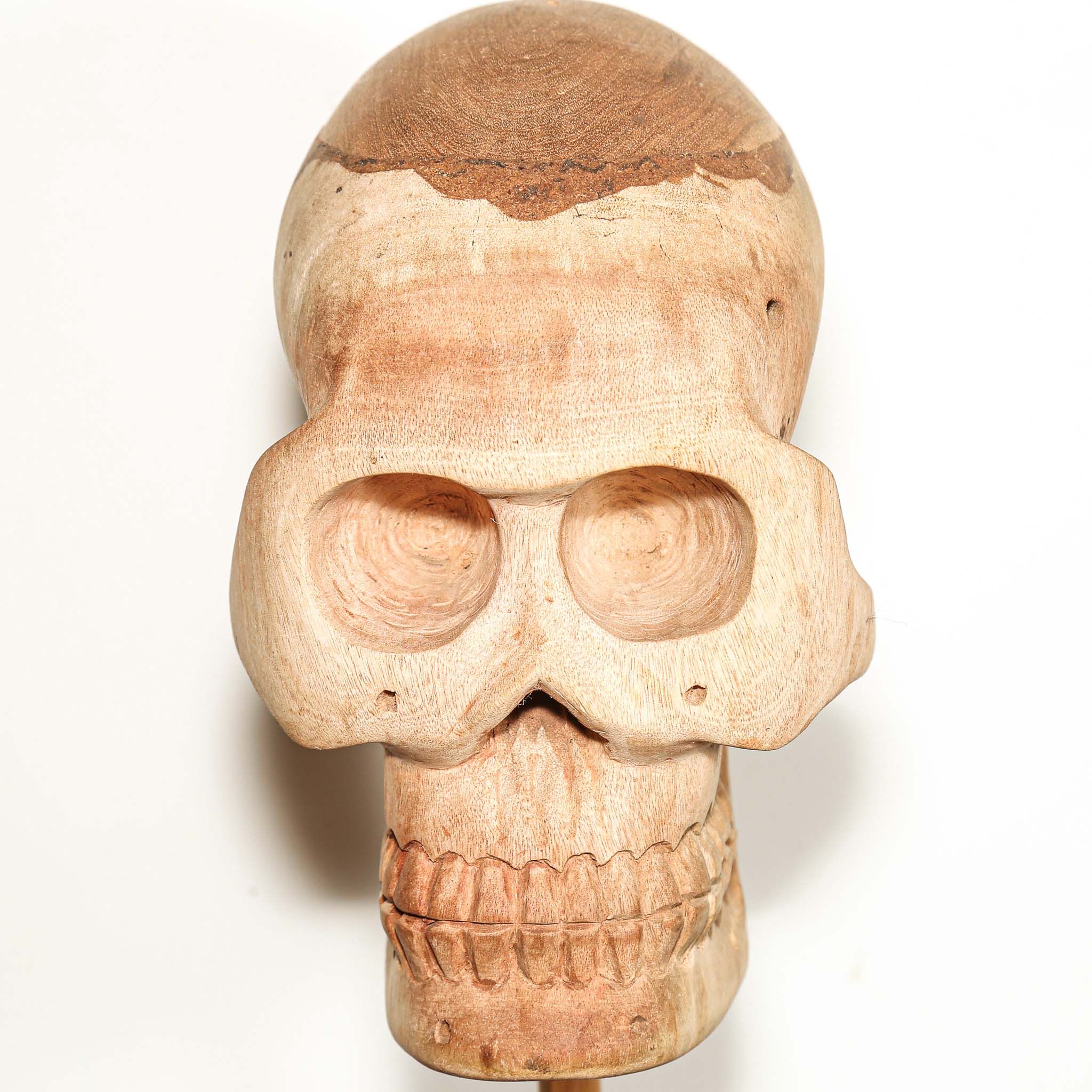 Hand Carved African Wooden human skull sculpture on a wooden base in a living room on a side table