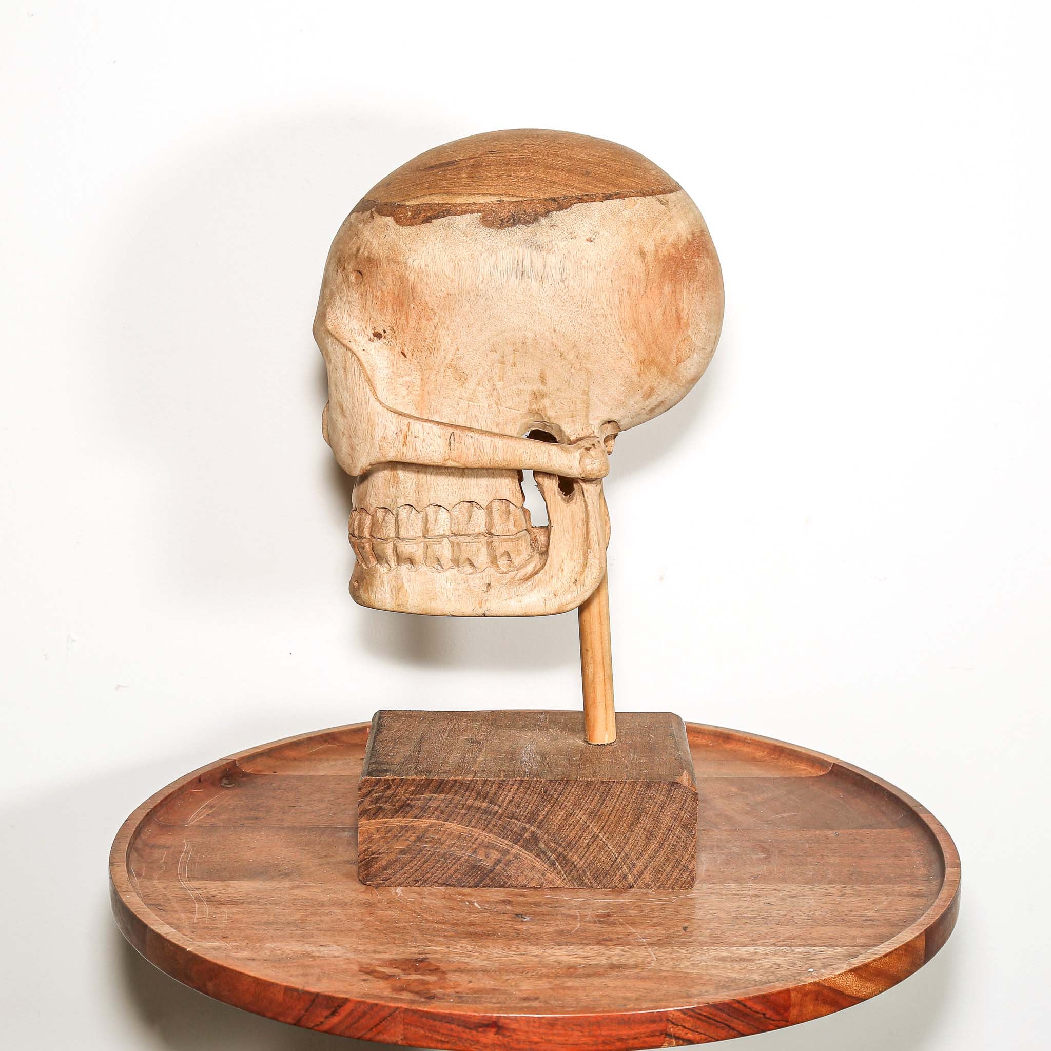 Hand Carved African Wooden human skull sculpture on a wooden base in a living room on a side table