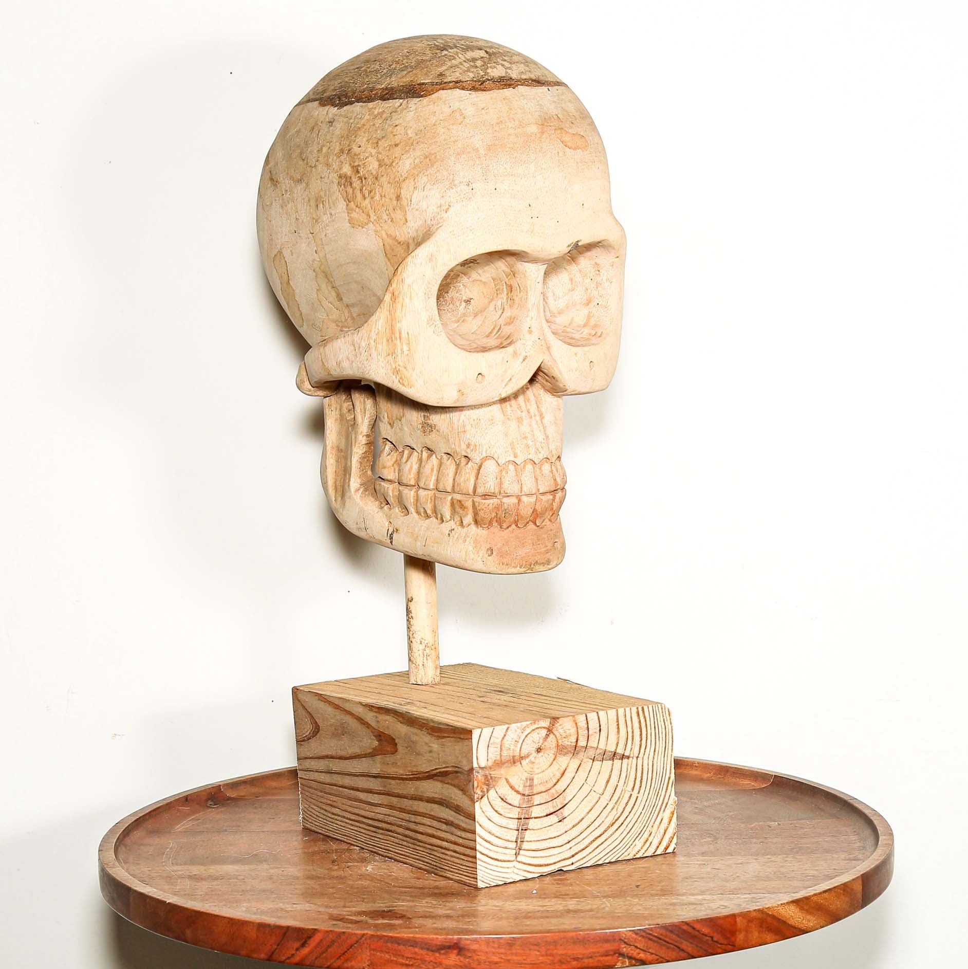 Wooden Skull sculpture on a stand with a white background made in Africa