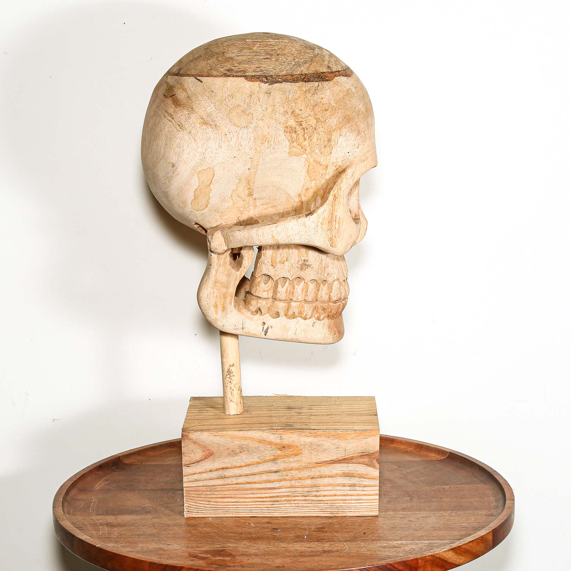 Wooden Skull sculpture on a stand with a white background made in Africa