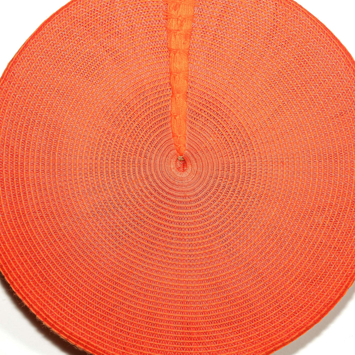 Colorful orange Zulu hat with a distinctive round woven design, displayed as bright African-inspired wall decoration