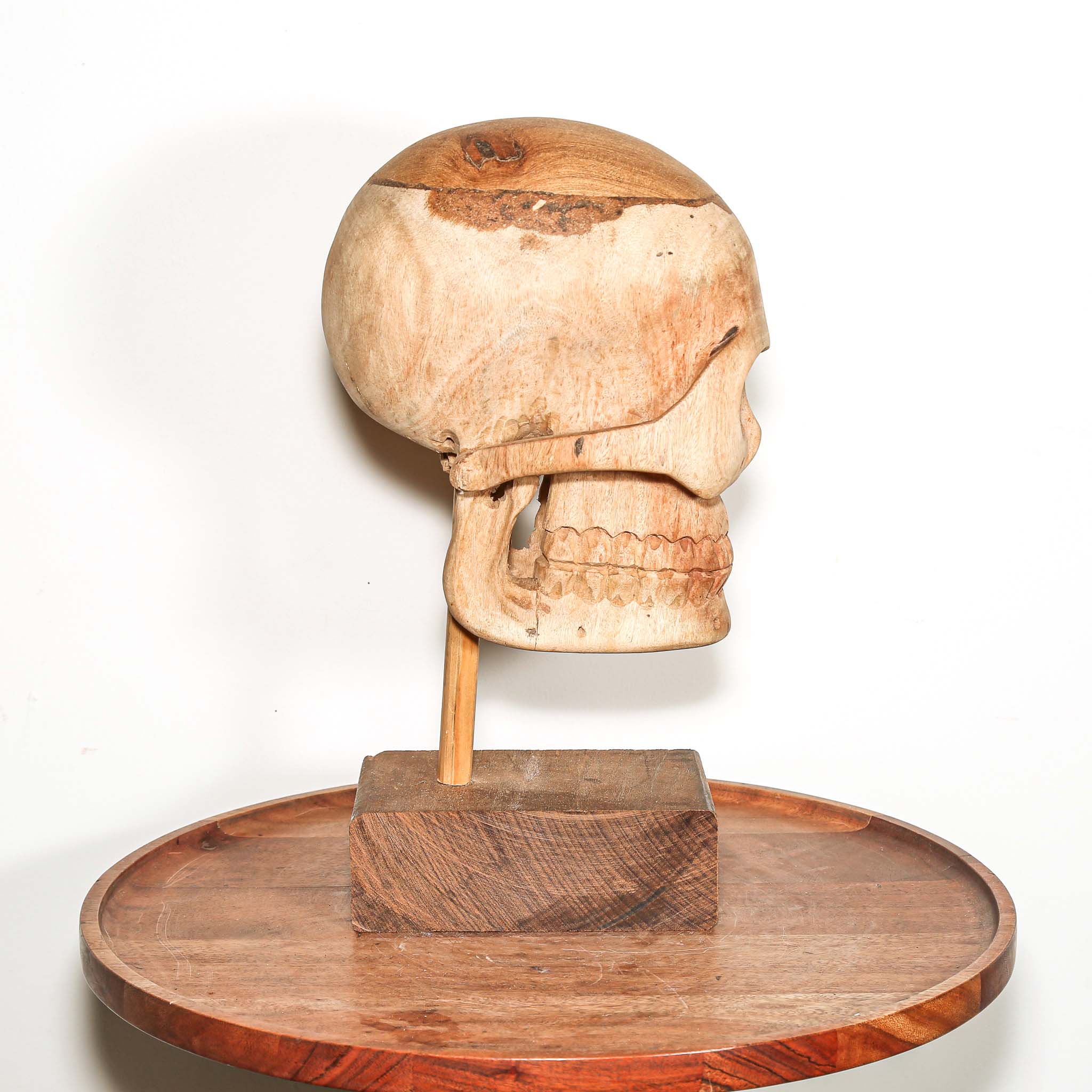 Hand Carved African Wooden human skull sculpture on a wooden base in a living room on a side table