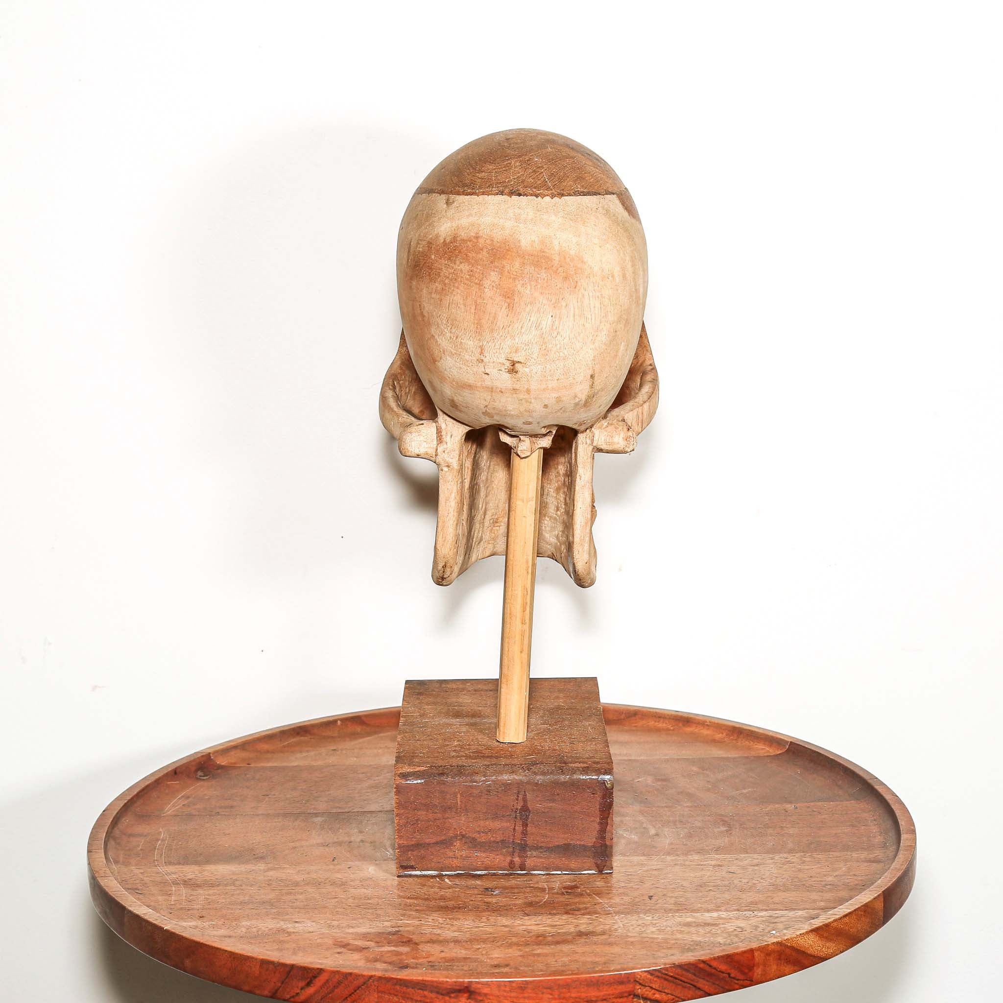 Hand Carved African Wooden human skull sculpture on a wooden base in a living room on a side table