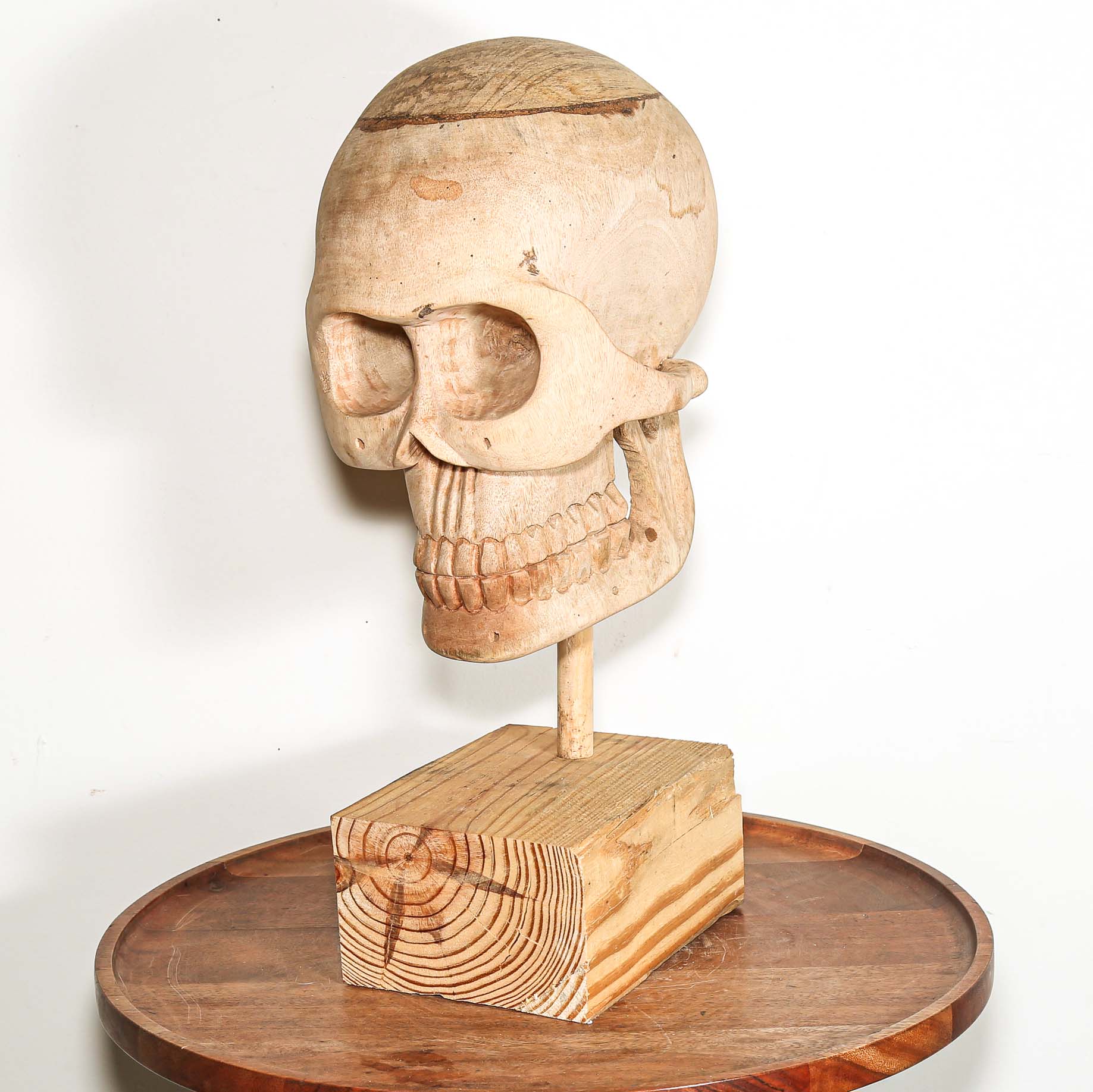 Wooden Skull sculpture on a stand with a white background made in Africa
