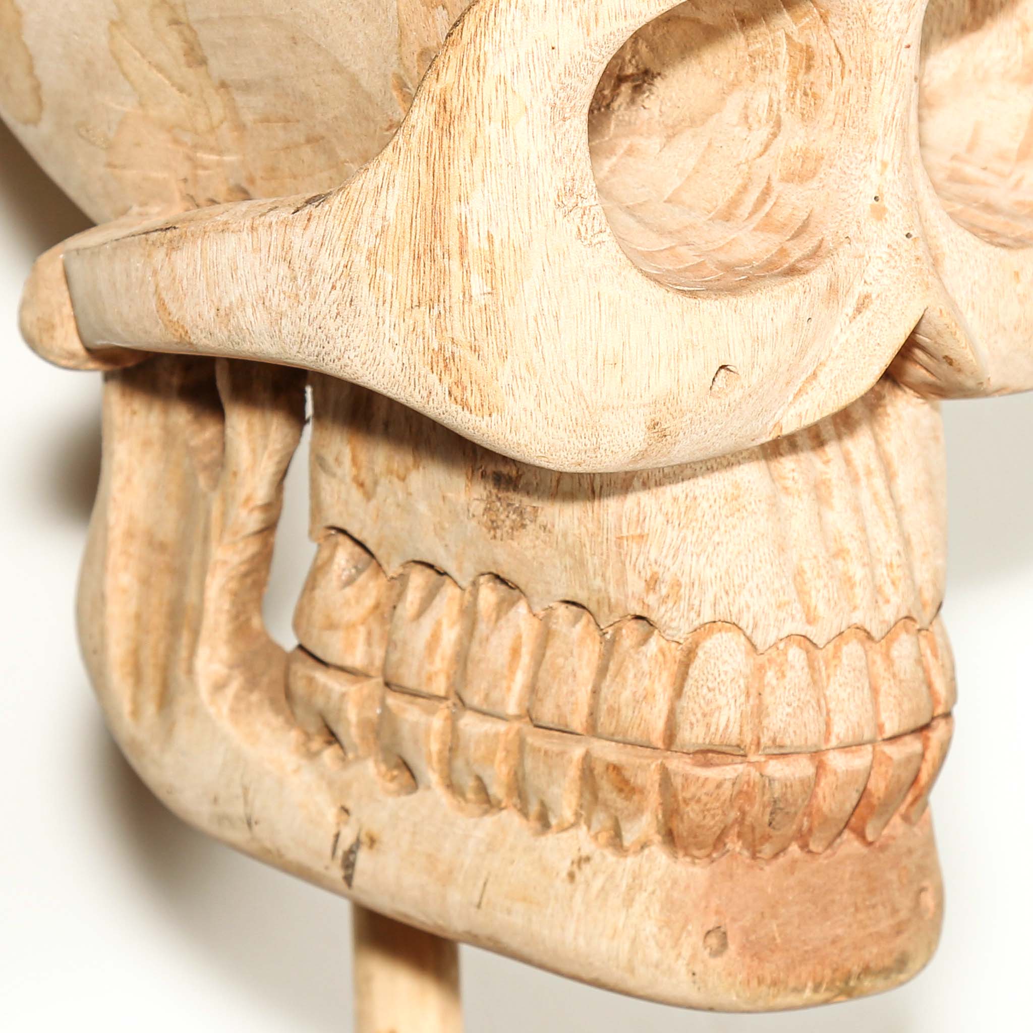 Close-up of a carved wooden skull with detailed features on a white background