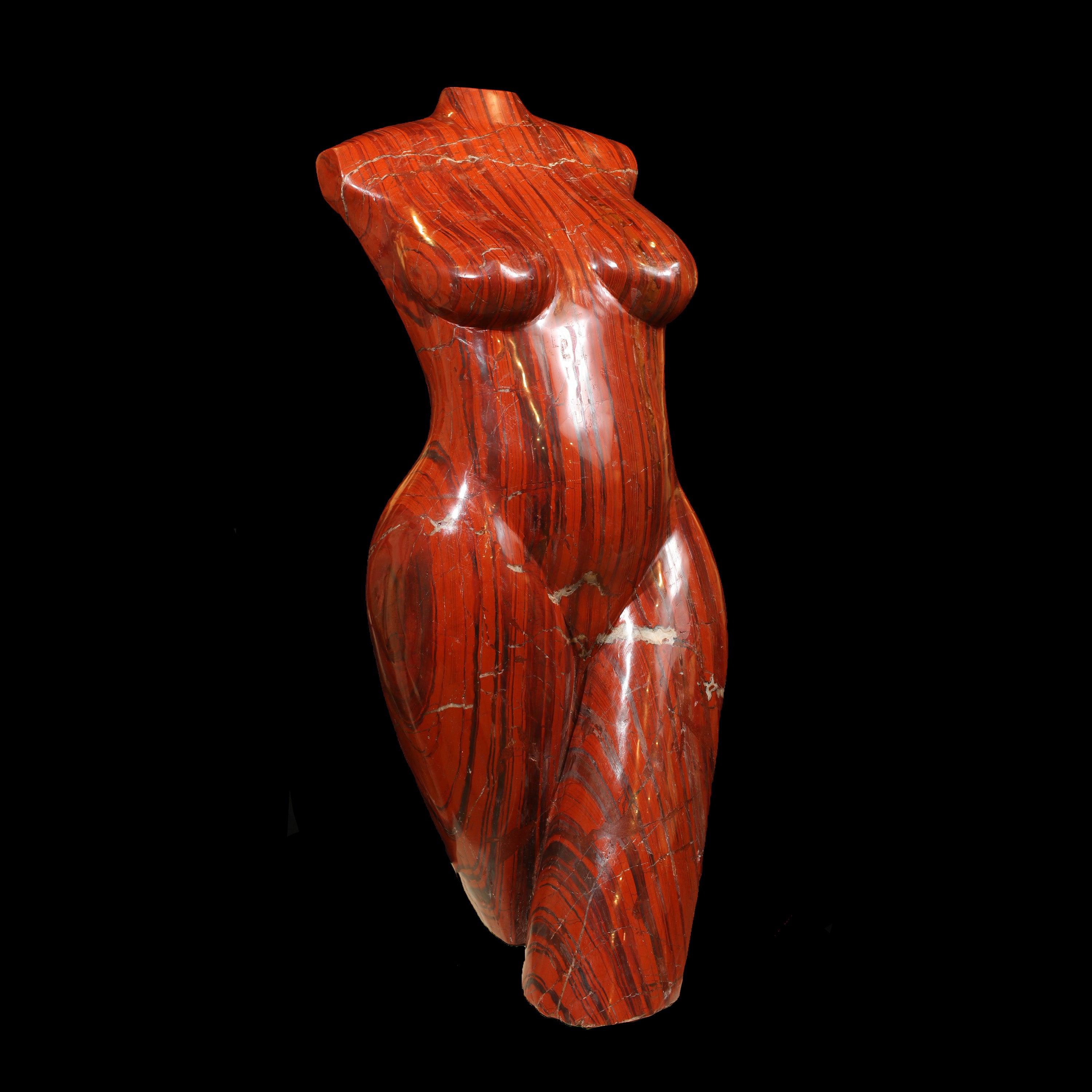 A free-standing red jasper stone torso sculpture with a textured and rugged surface.