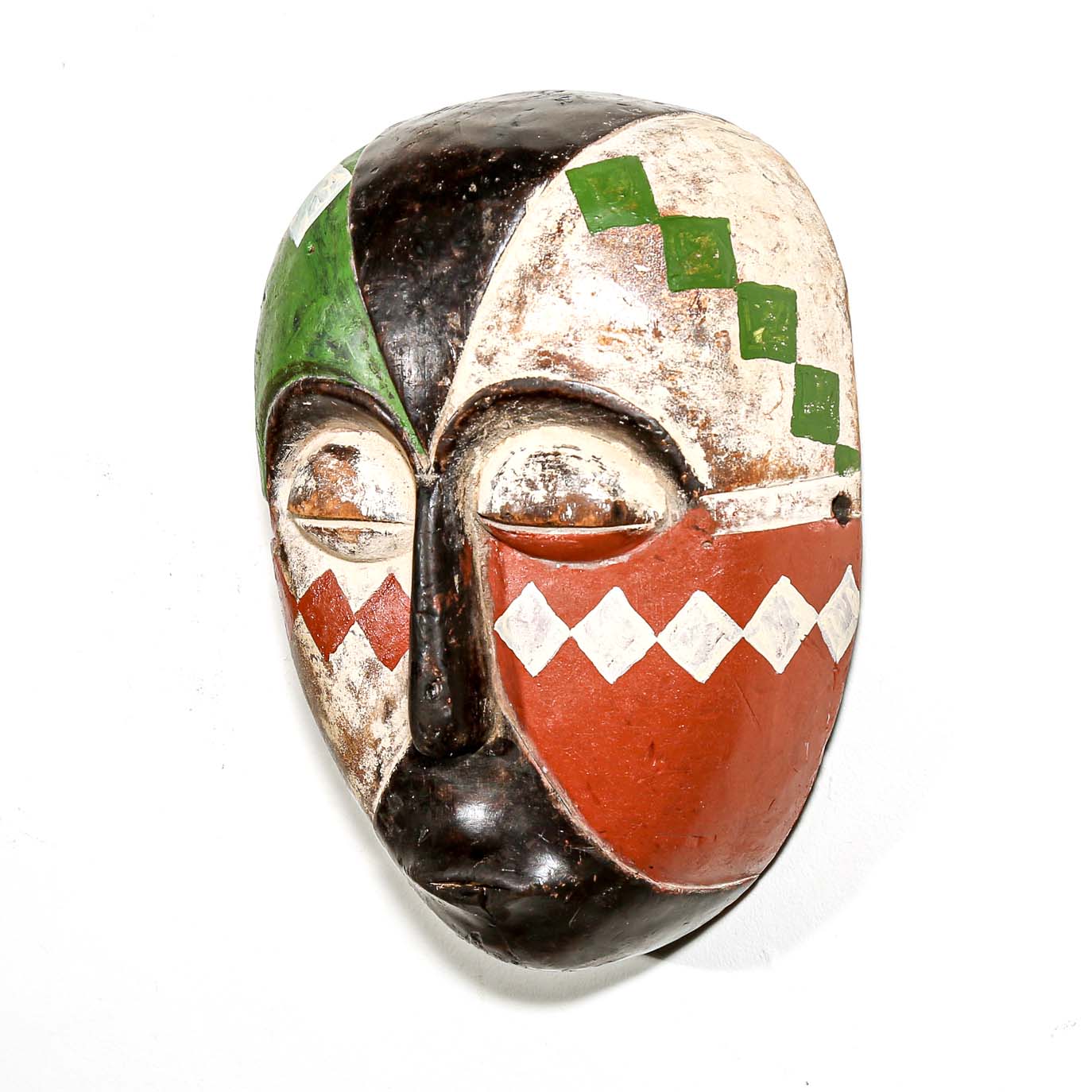 Colorful Aduma African wood mask with geometric patterns on a white bedroom wall