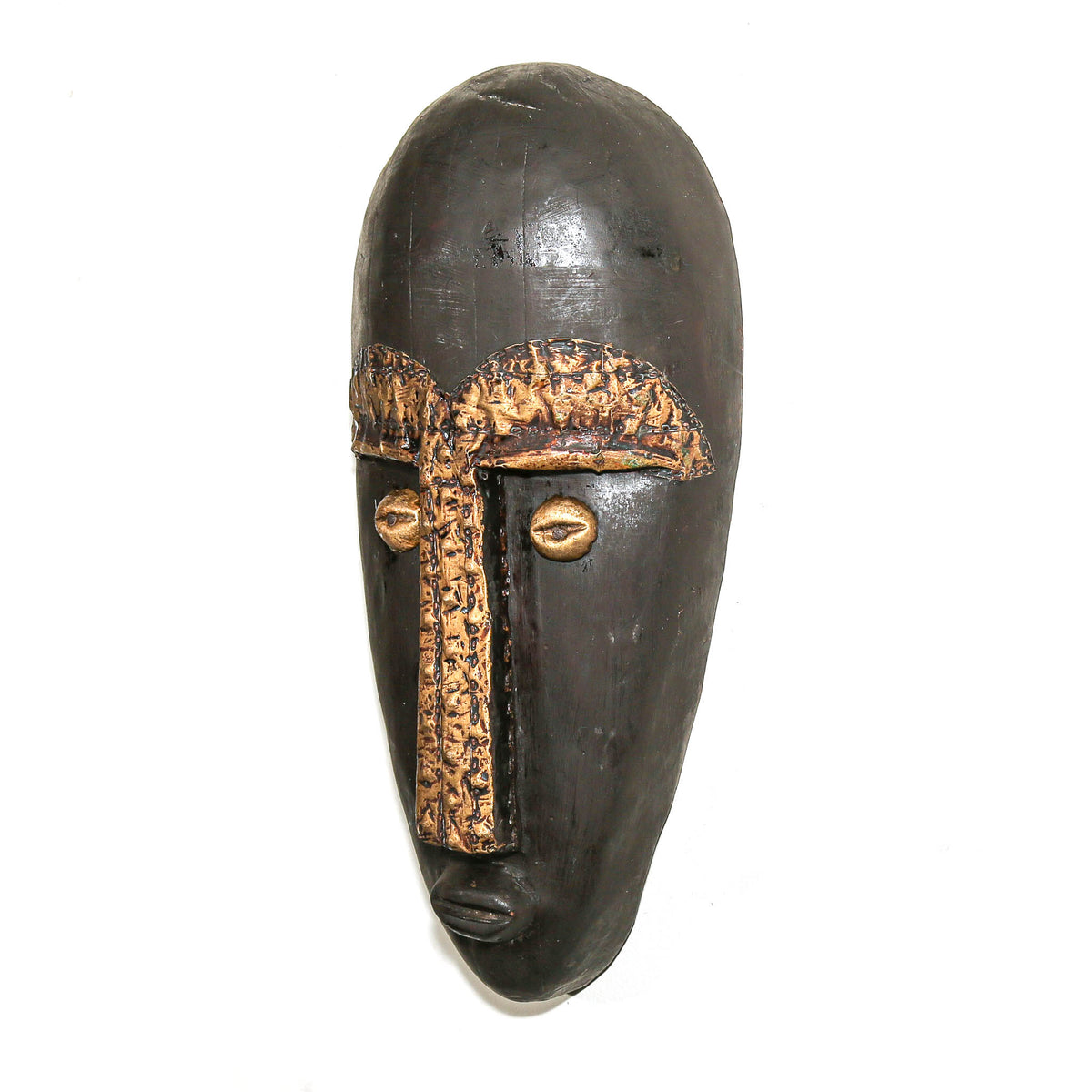 A dark carved wooden mask with a textured patterned brow band, vertical nose strip, and metallic gold-toned eyes, shown against a plain white background.