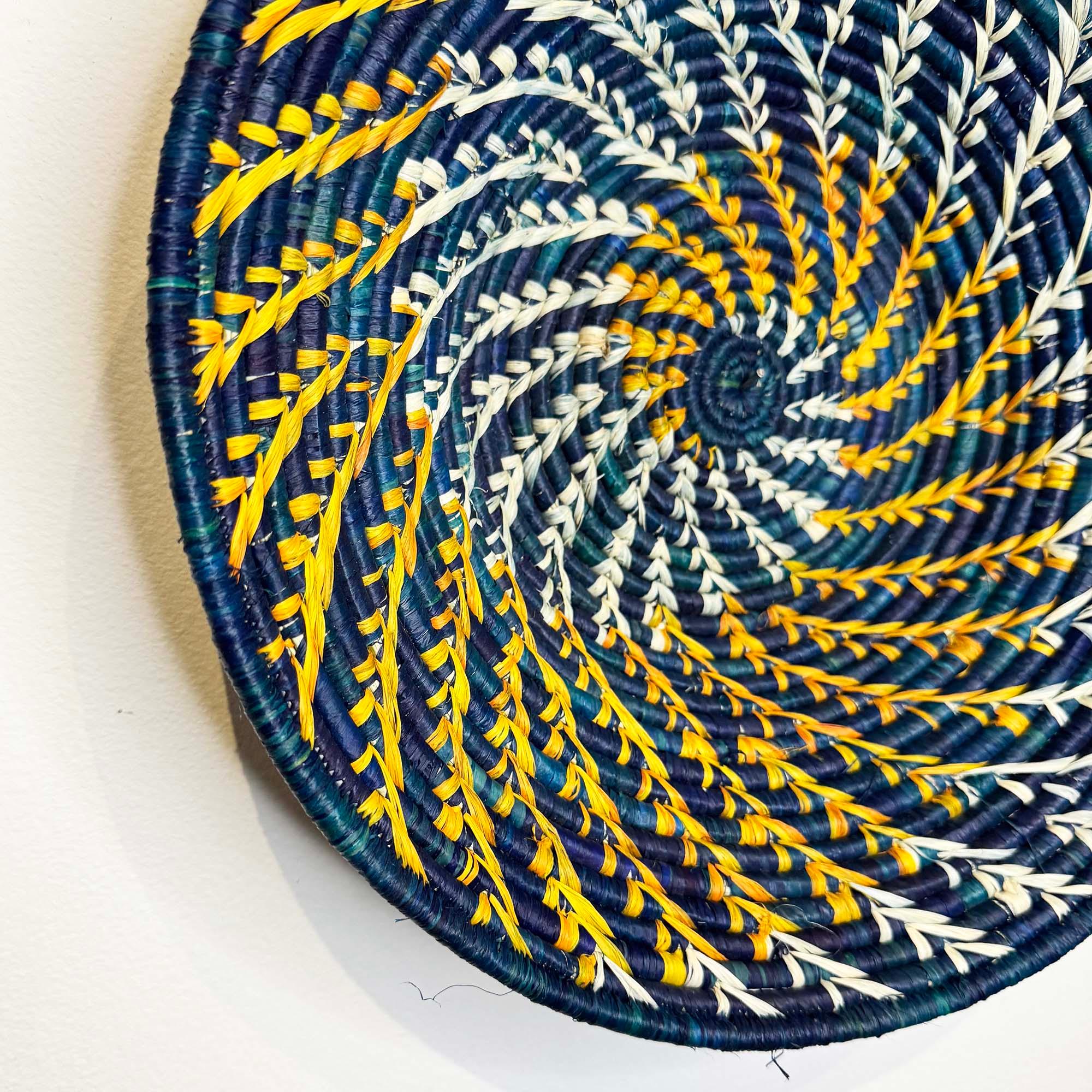 Blue Woven Basket Handmade in Uganda hanging on a wall with a close up