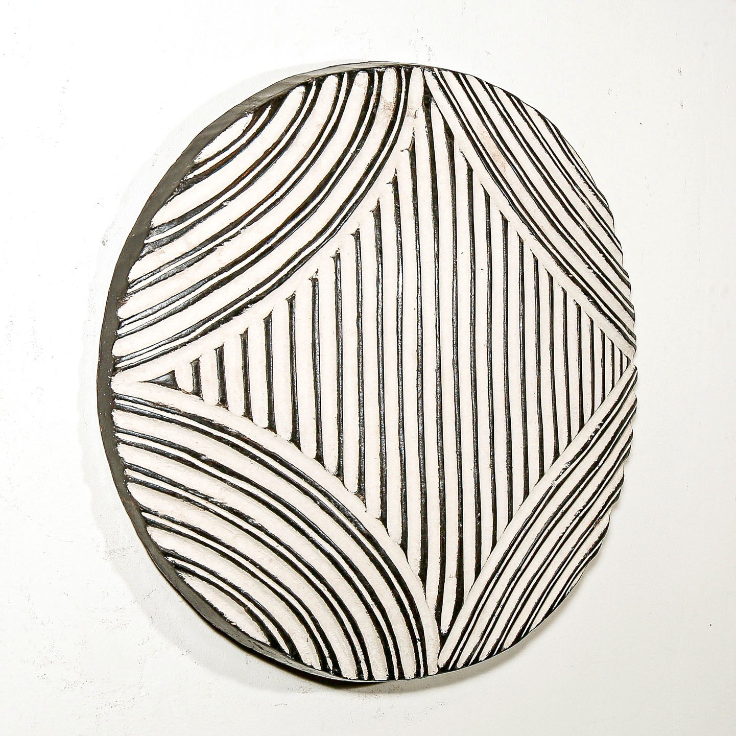 Round wood wall decor with rustic African traditional striped pattern on a white living room wall