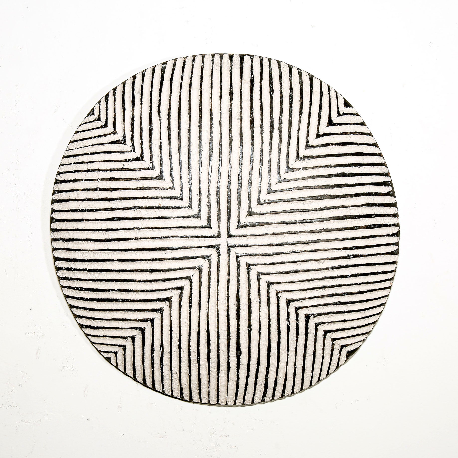 Round wood wall decor with rustic African traditional striped pattern on a white living room wall