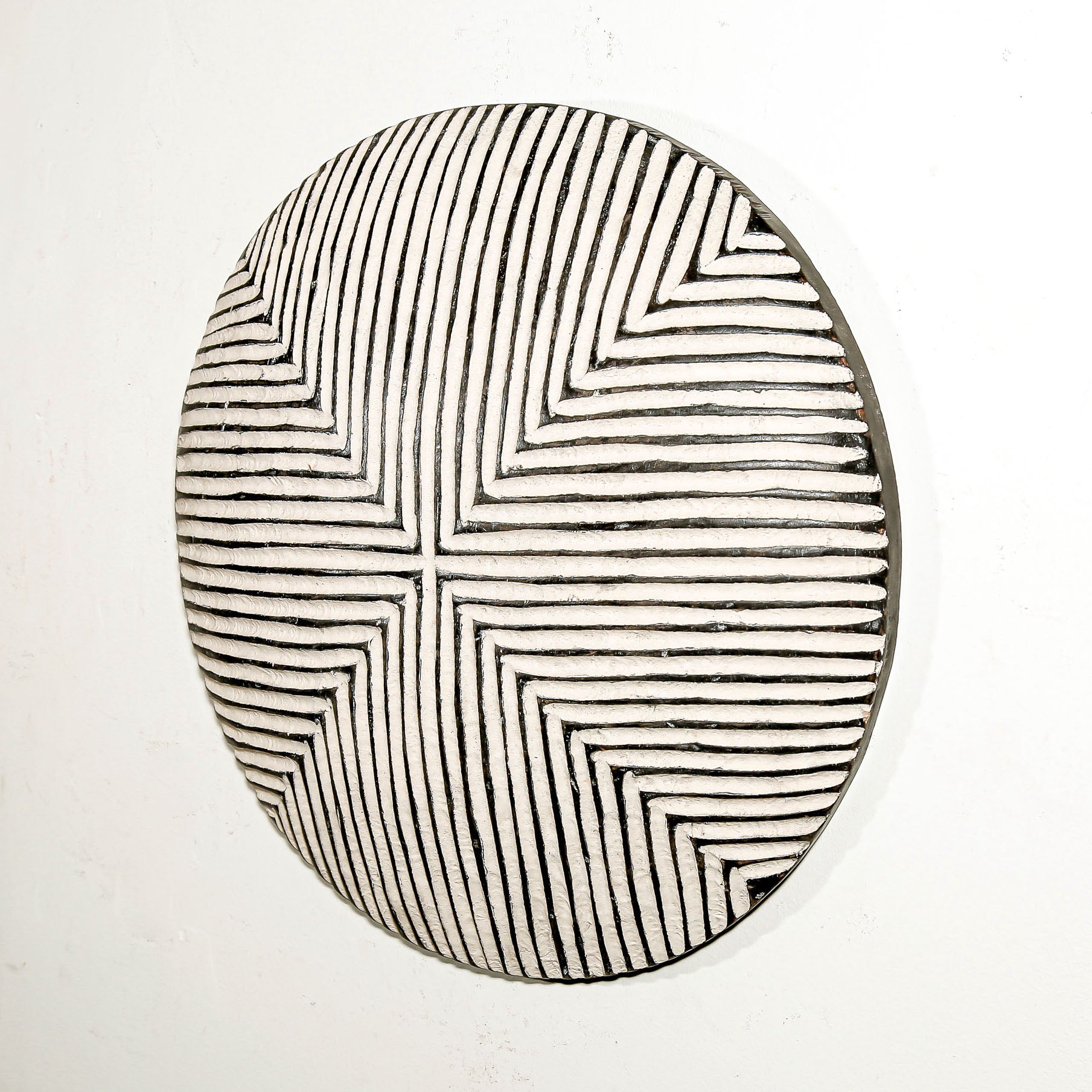 Round wood wall decor with rustic African traditional striped pattern on a white living room wall