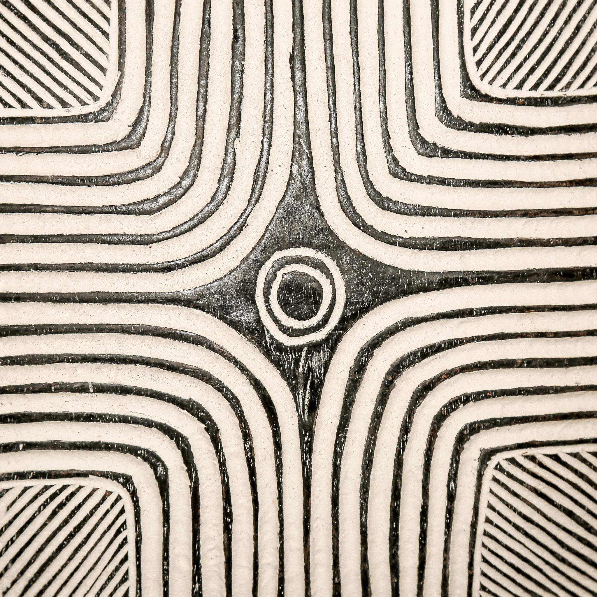 Round wood wall decor with rustic African traditional striped pattern on a white living room wall