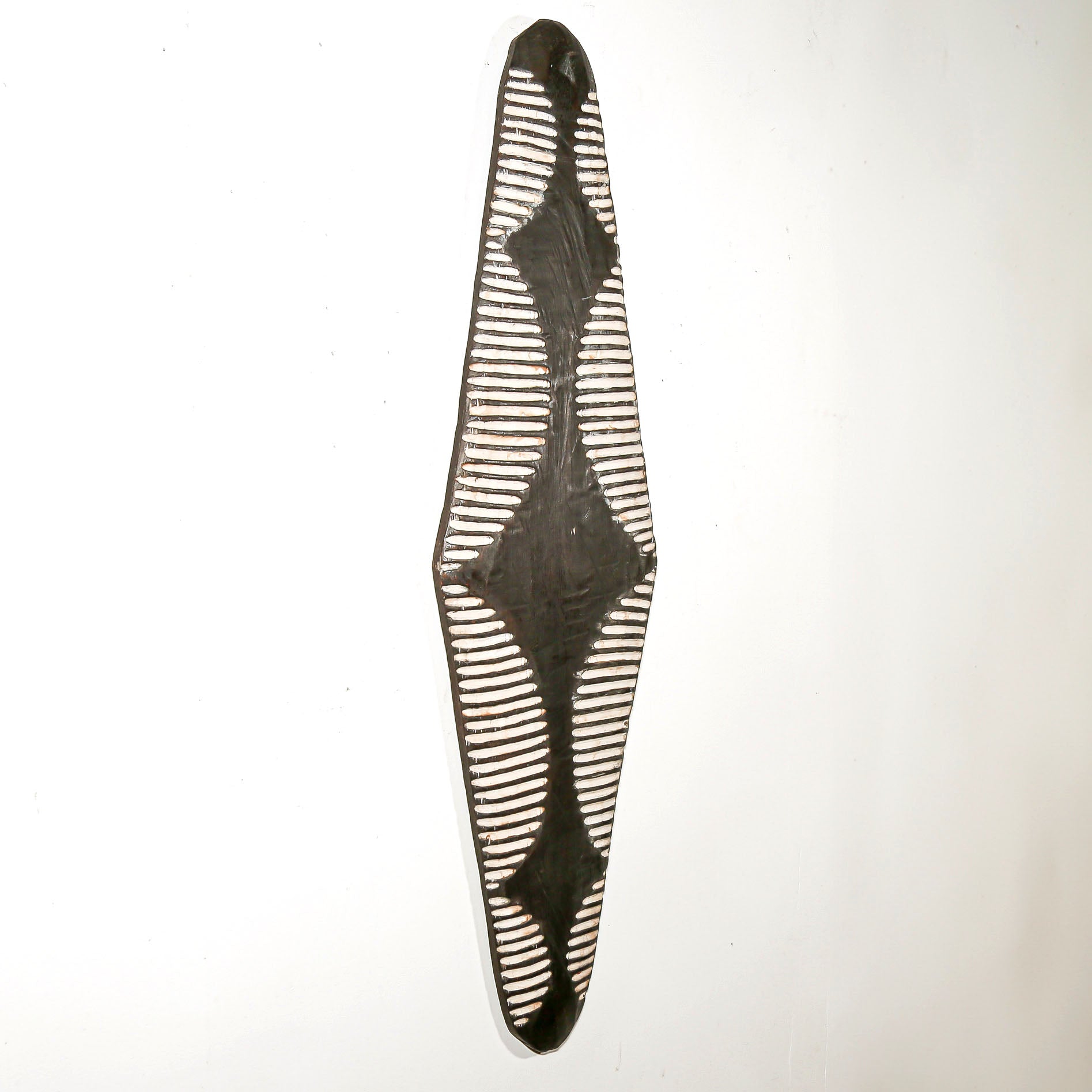 Long wood wall decor with rustic African traditional striped pattern on a white living room wall