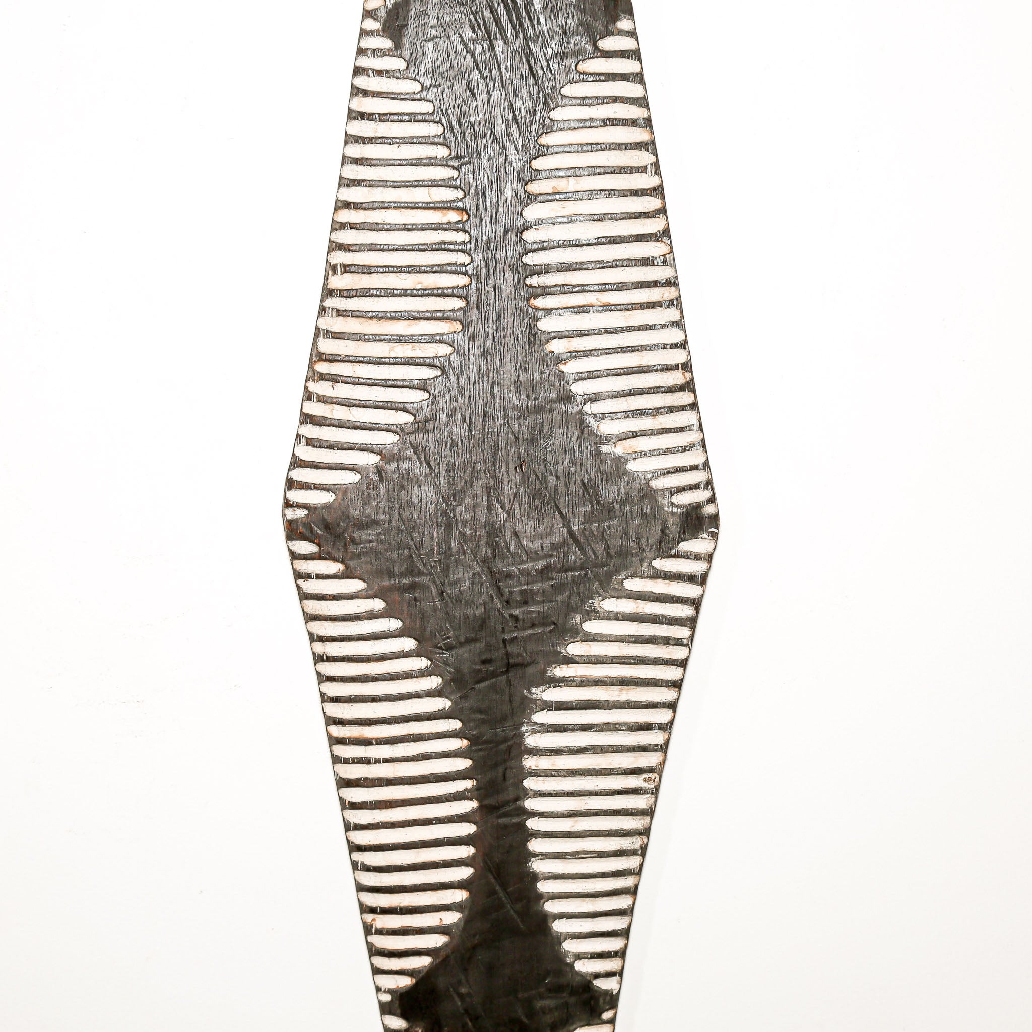 Long wood wall decor with rustic African traditional striped pattern on a white living room wall