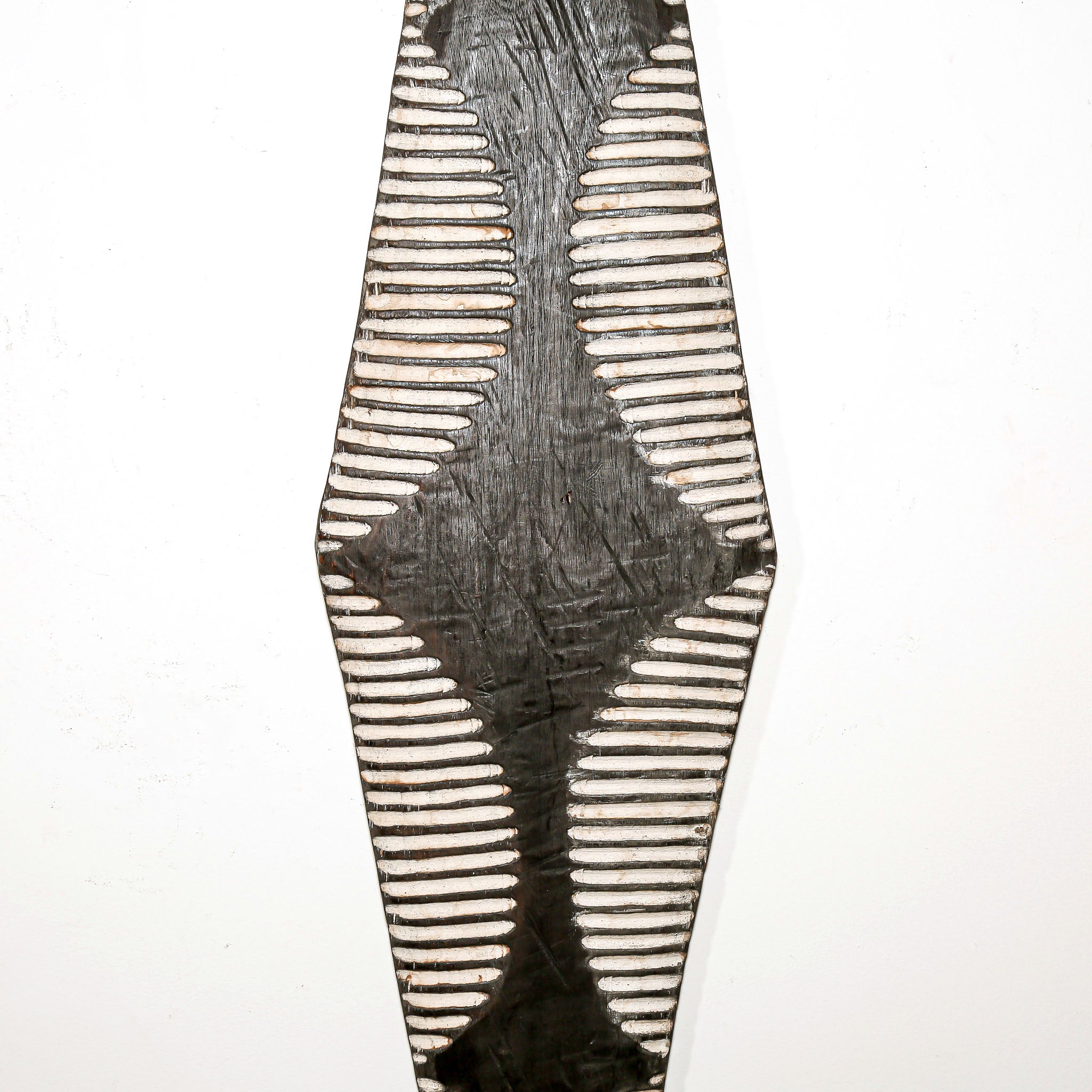 Long wood wall decor with rustic African traditional striped pattern on a white living room wall