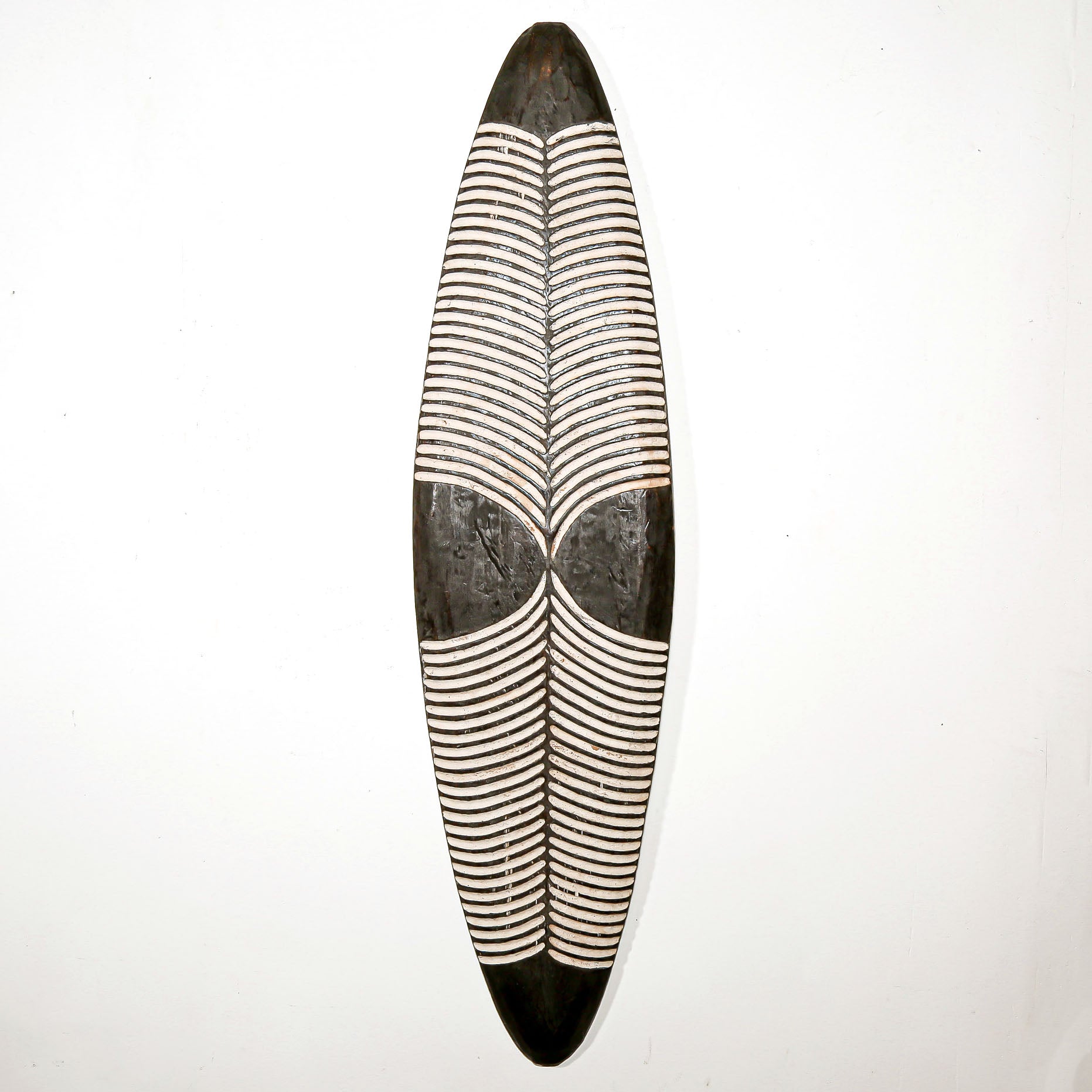 Long wood wall decor with rustic African traditional striped pattern on a white living room wall