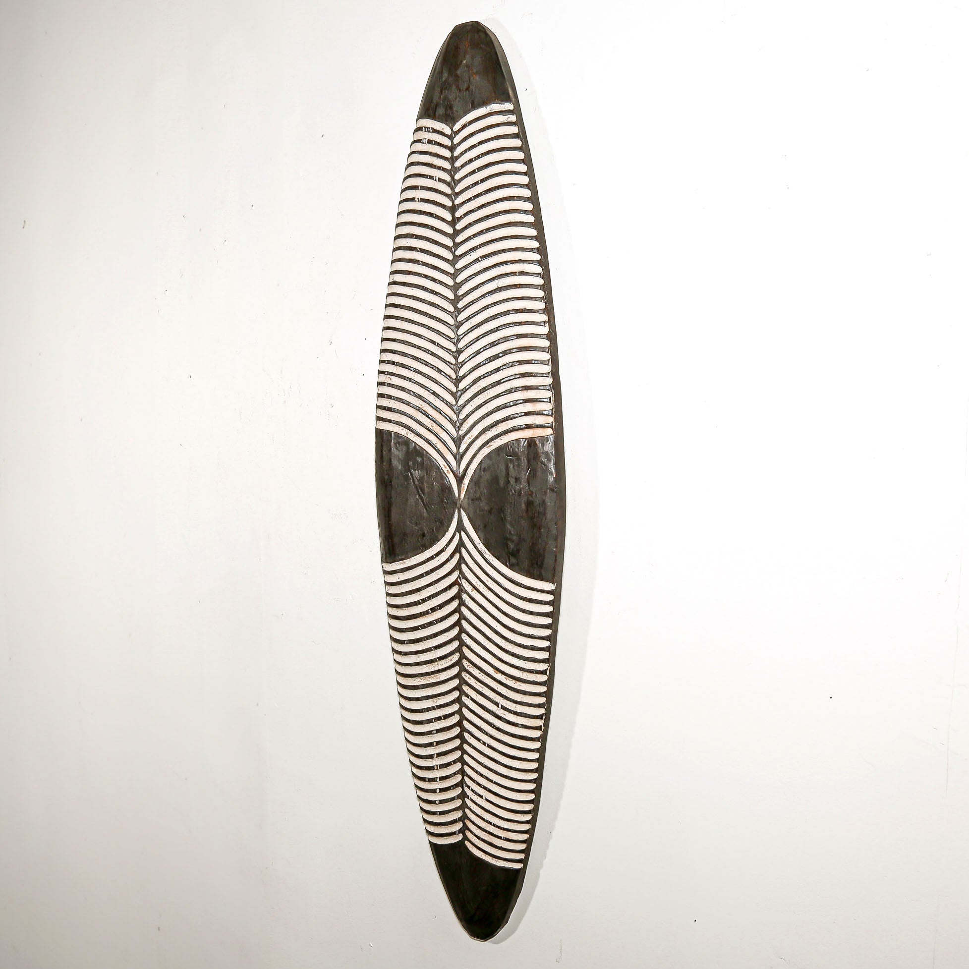 Long wood wall decor with rustic African traditional striped pattern on a white living room wall