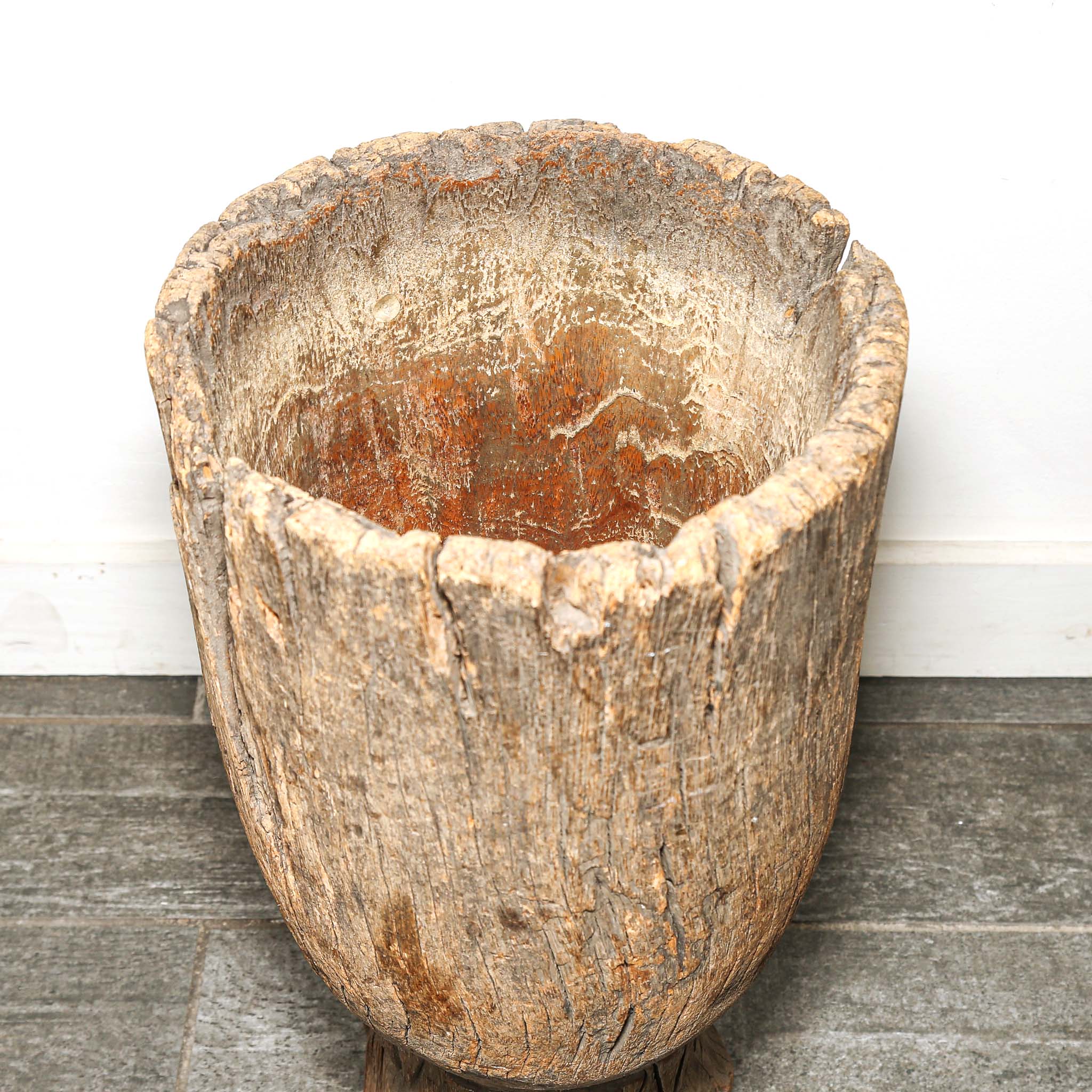 Vintage wooden planter on a wooden floor with a white wall background