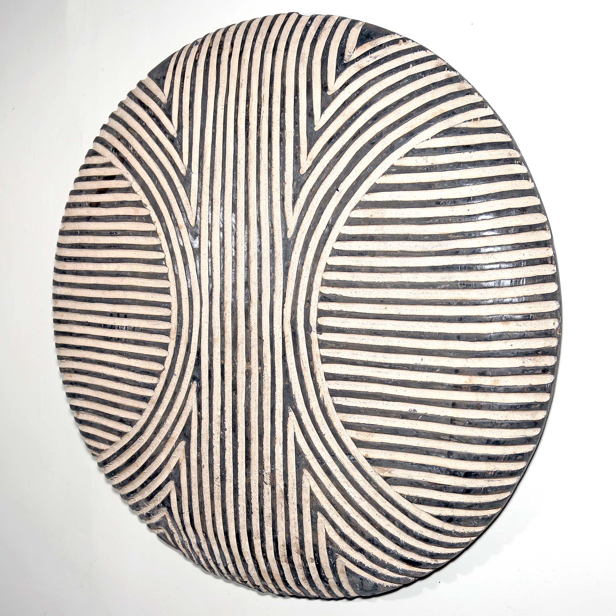 Round wood African art wall hanging for sale with black and white striped pattern on a white background living room design