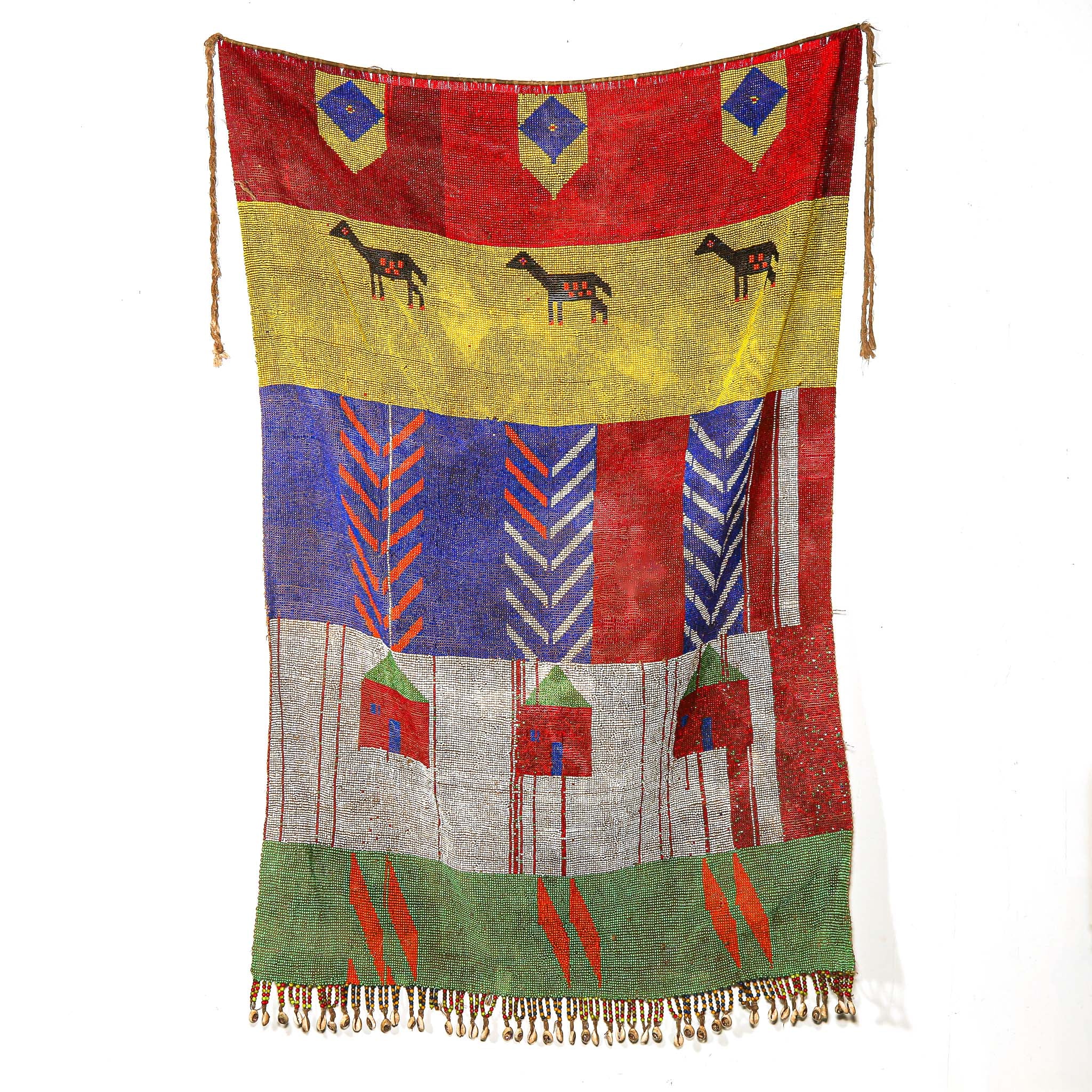 Colorful beaded textile with geometric patterns hanging on a white wall