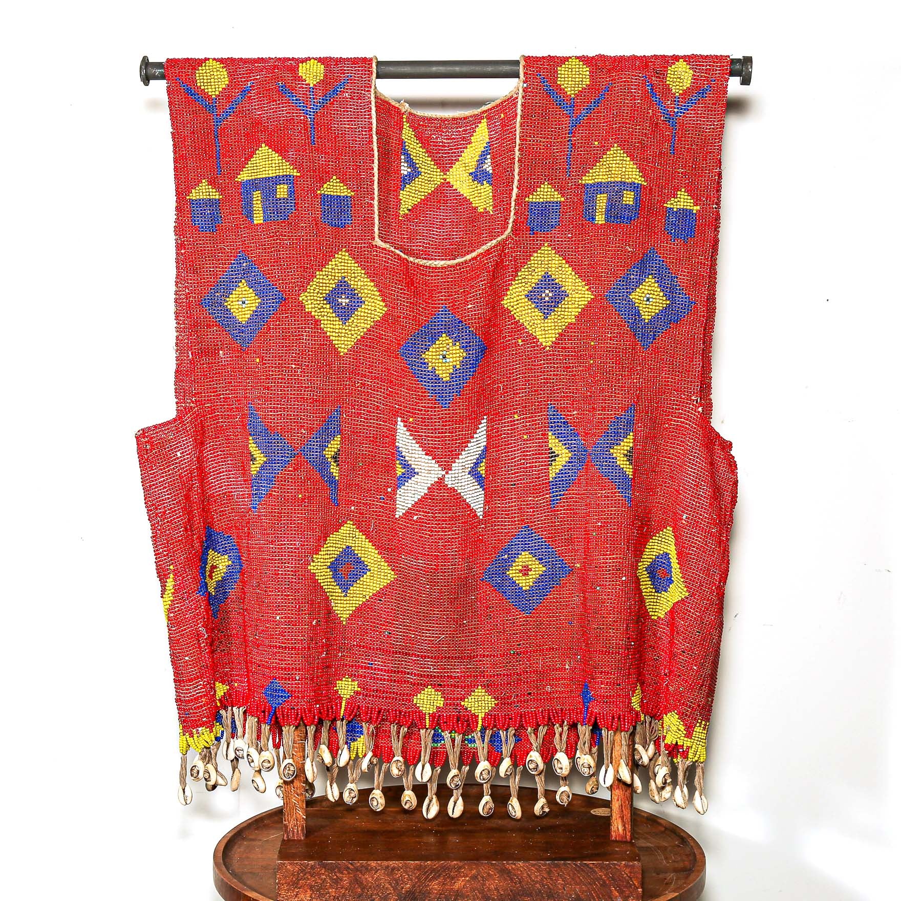 Red beaded garment for sculptural display with geometric patterns on a stand against a white background. high quality collectable African art