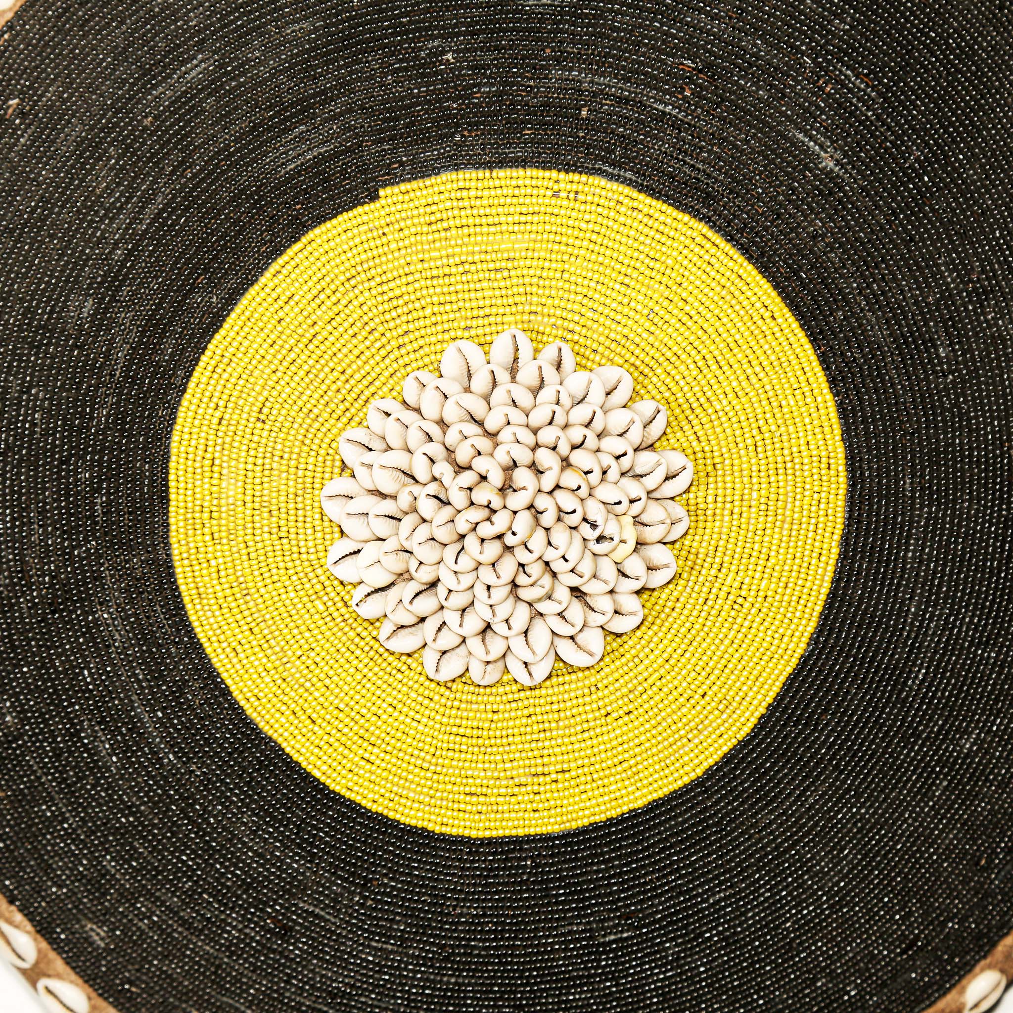 Decorative item with a yellow circle and white floral pattern on a black background