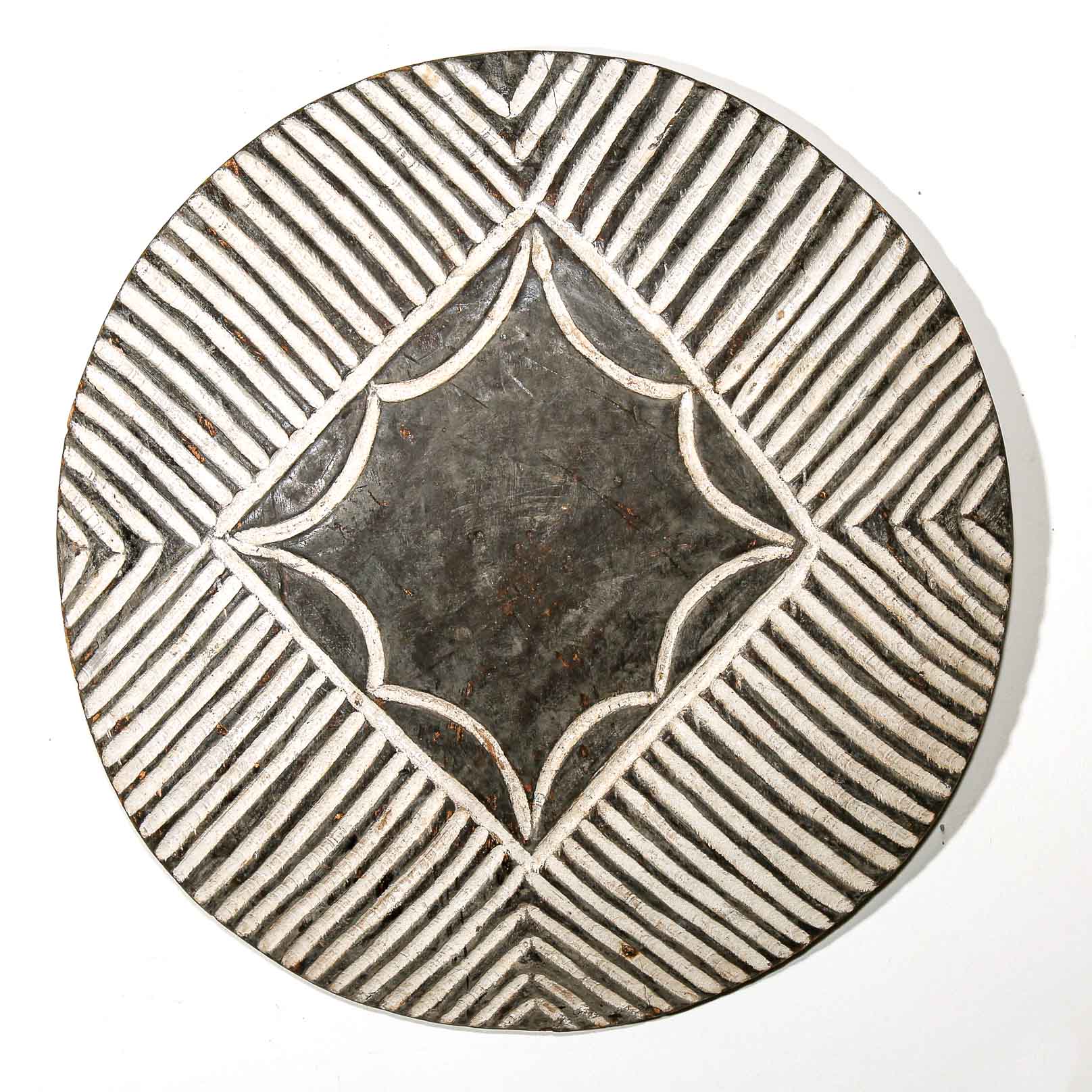 Decorative wall hanging round shield with geometric pattern on a white wall background