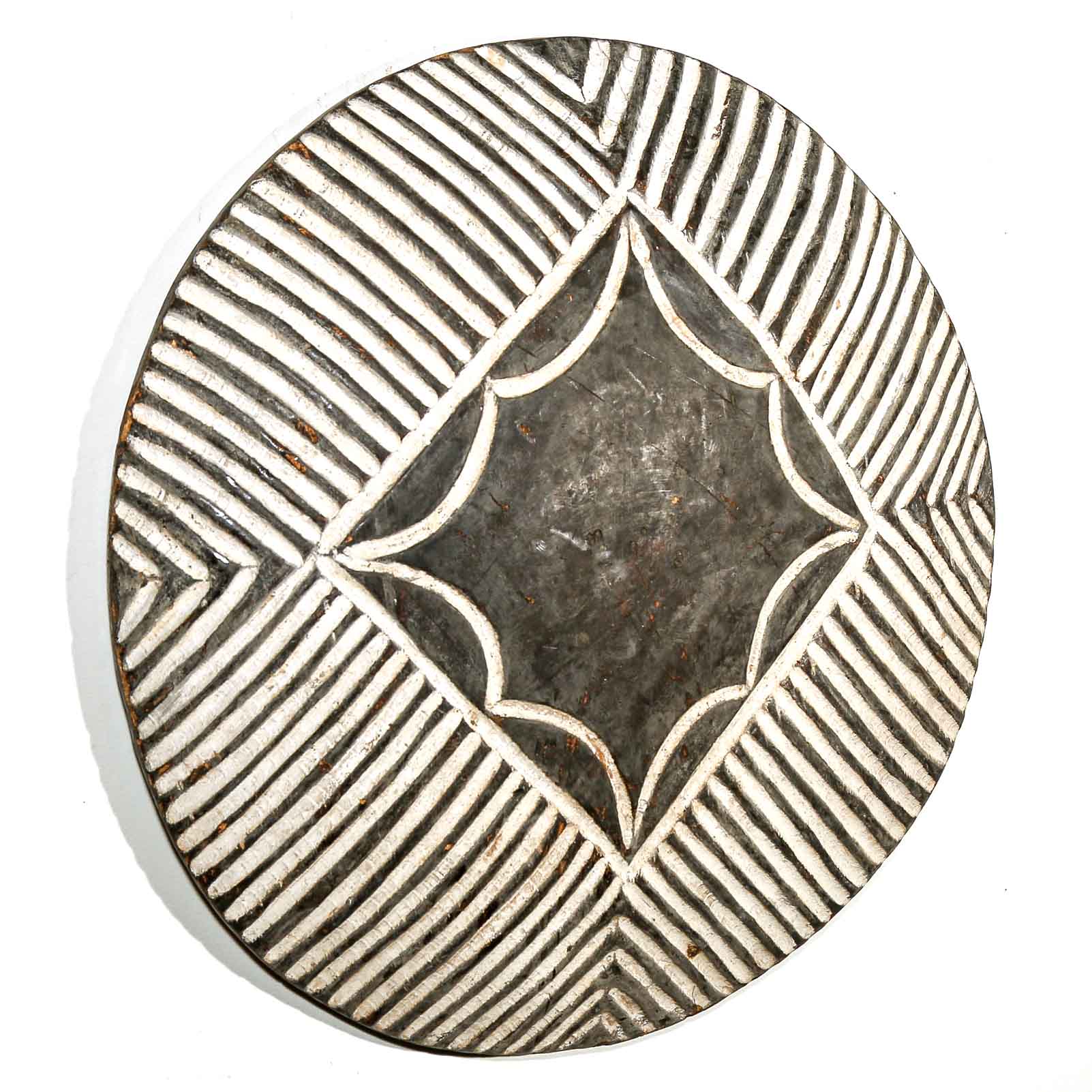 Decorative wall hanging round shield with geometric pattern on a white wall background
