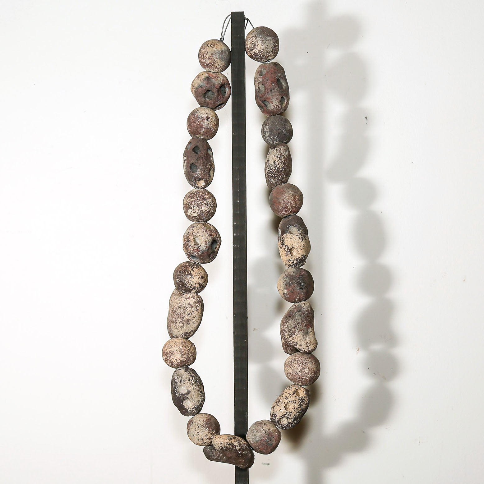 Contemporary volcanic rock necklace sculpture displayed on stand with hand carved stone beads for modern home decor