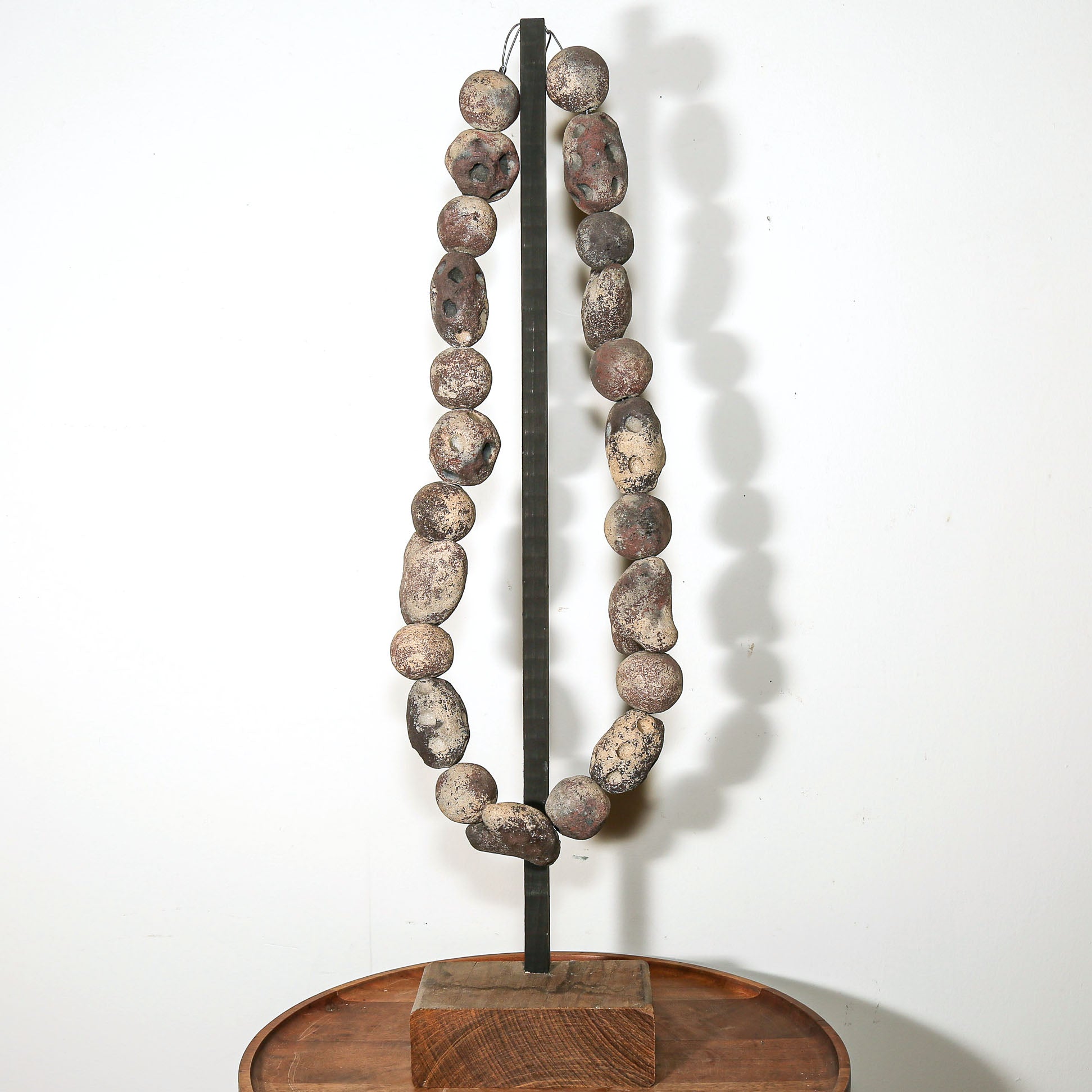 Hand carved volcanic stone bead necklace sculpture presented as contemporary art object on wooden base