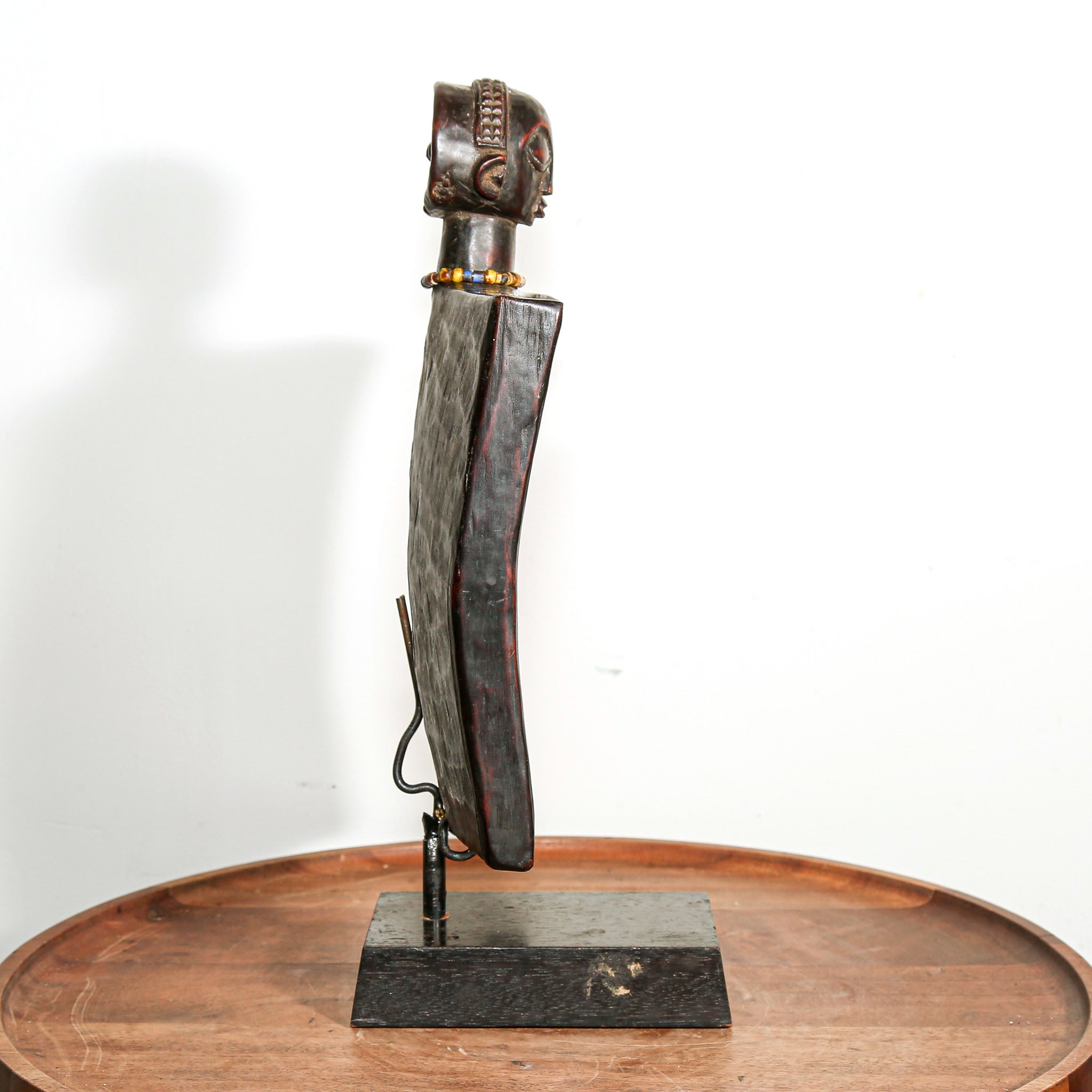 African wooden story telling art with metallic accents on a stand against a white background