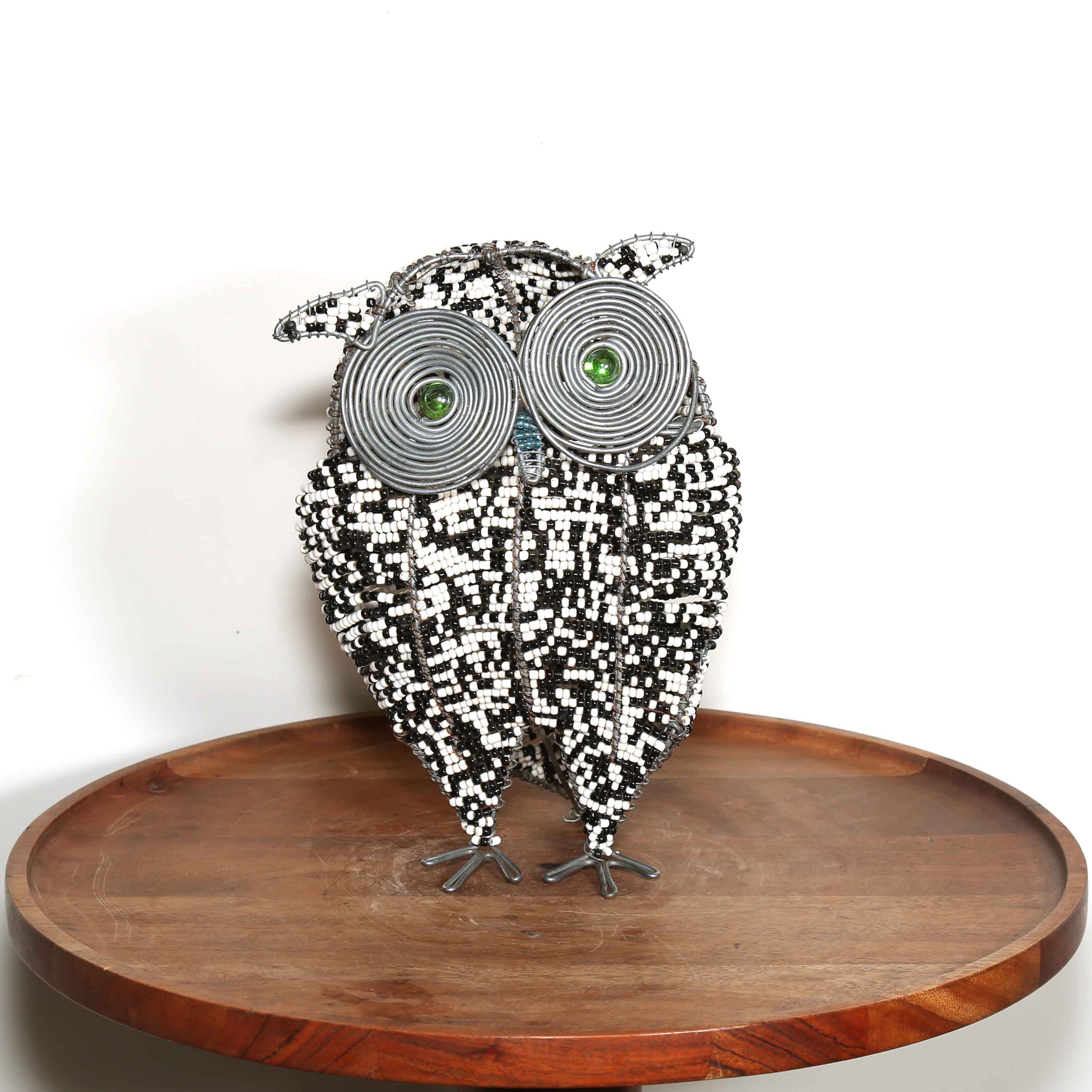 Decorative owl sculpture made from beads on a wooden platform with a white background