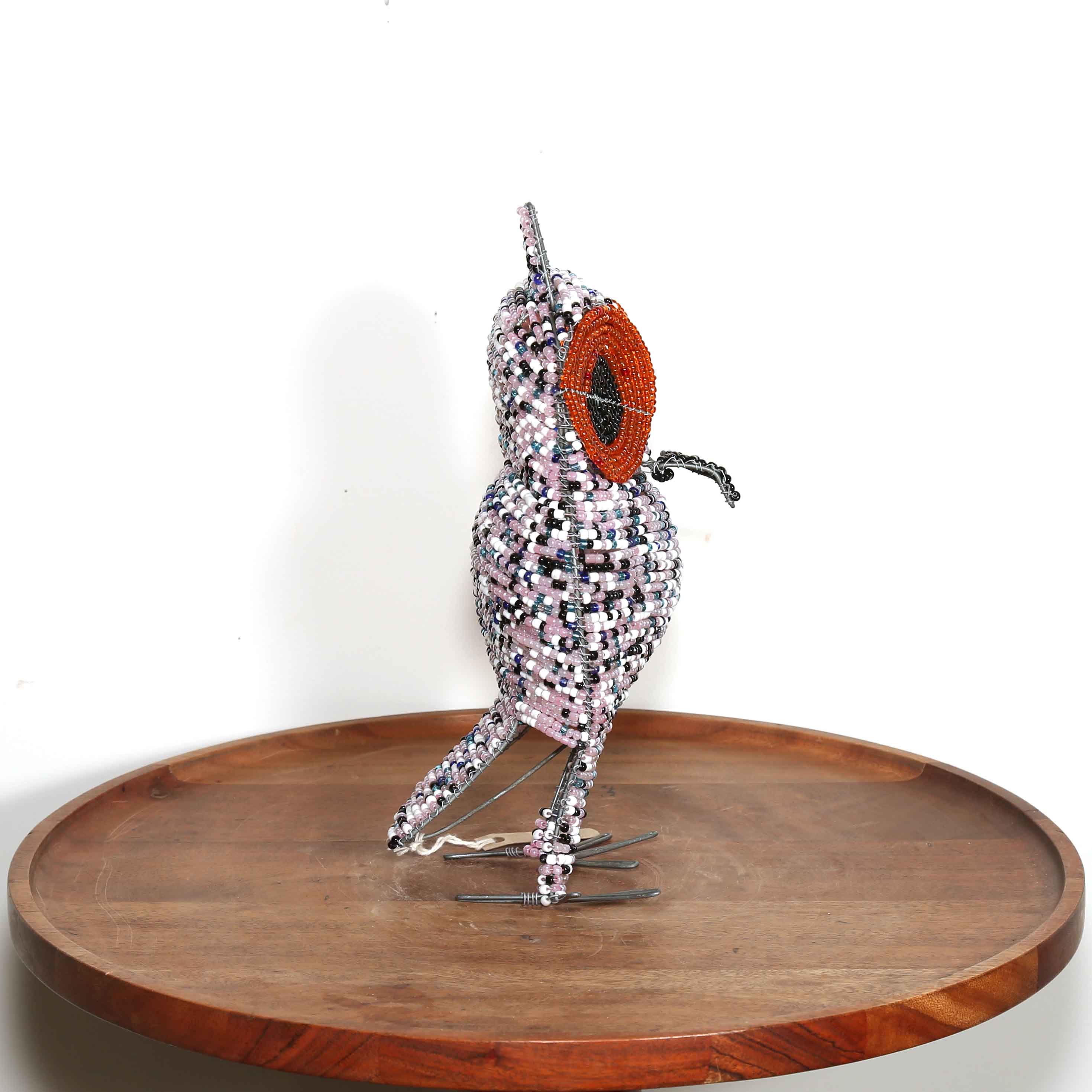 speckled pink African owl artwork with black and orange eyes view from the side