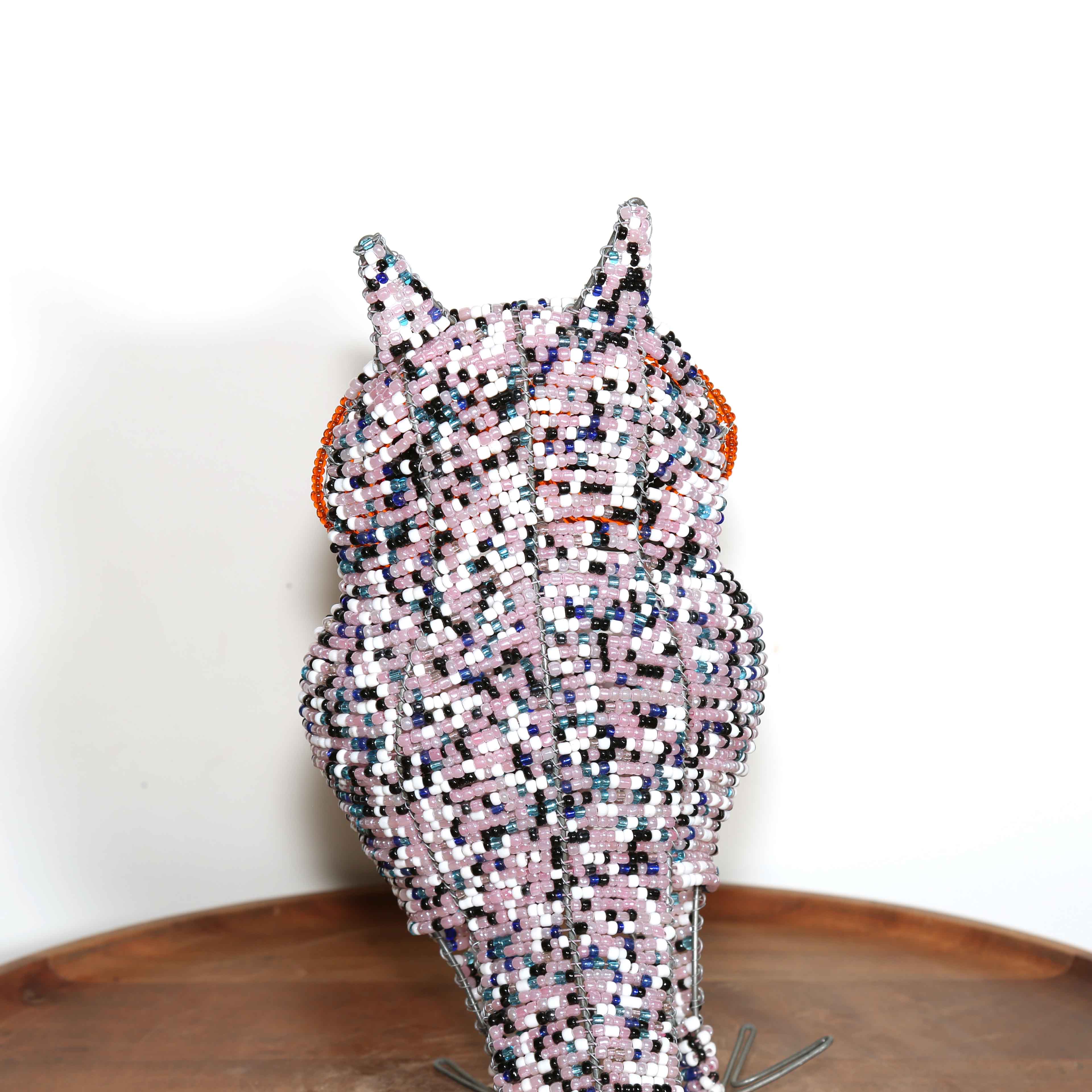 speckled pink African owl artwork with black and orange eyes detail of the beads