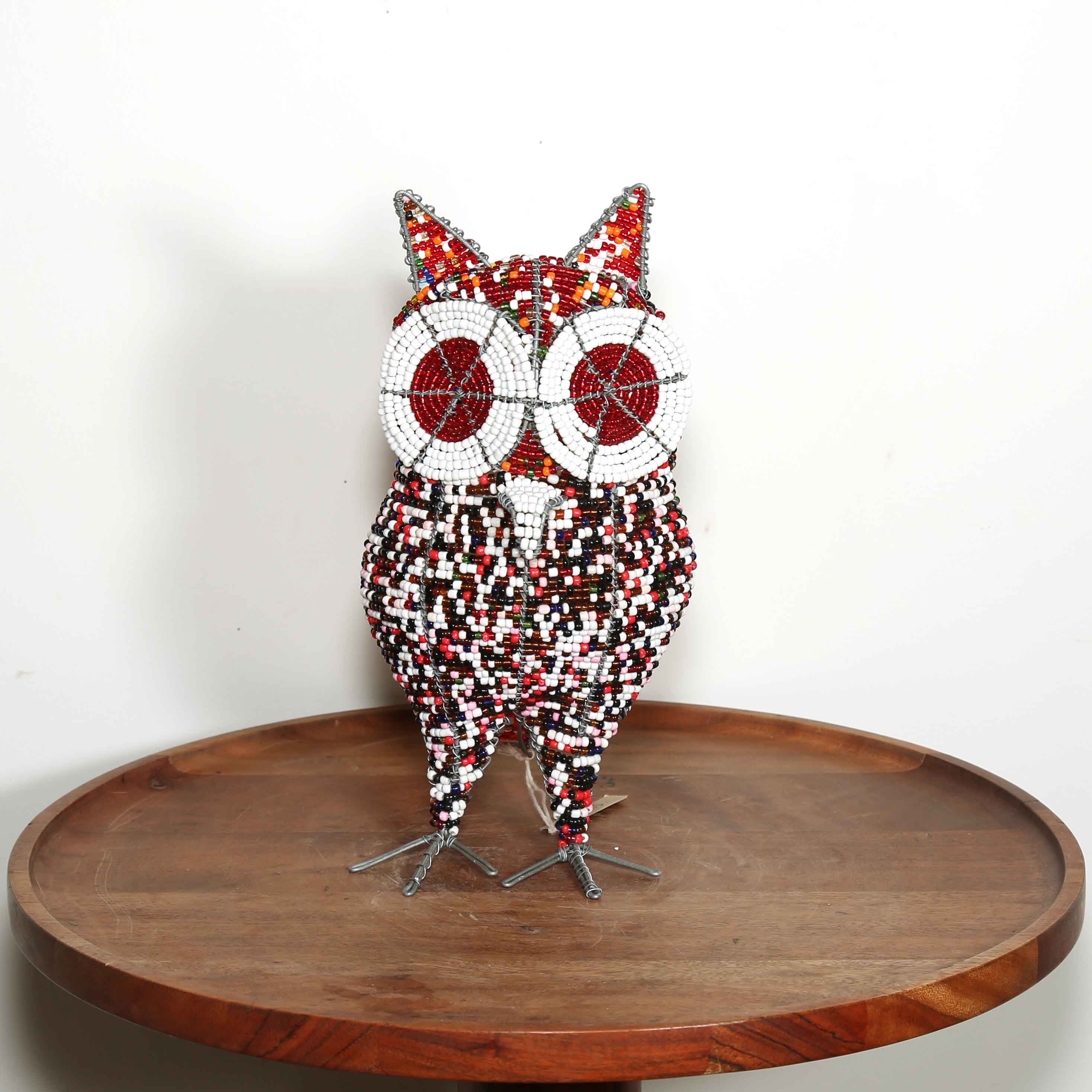 Decorative owl sculpture on a wooden table with a white background.