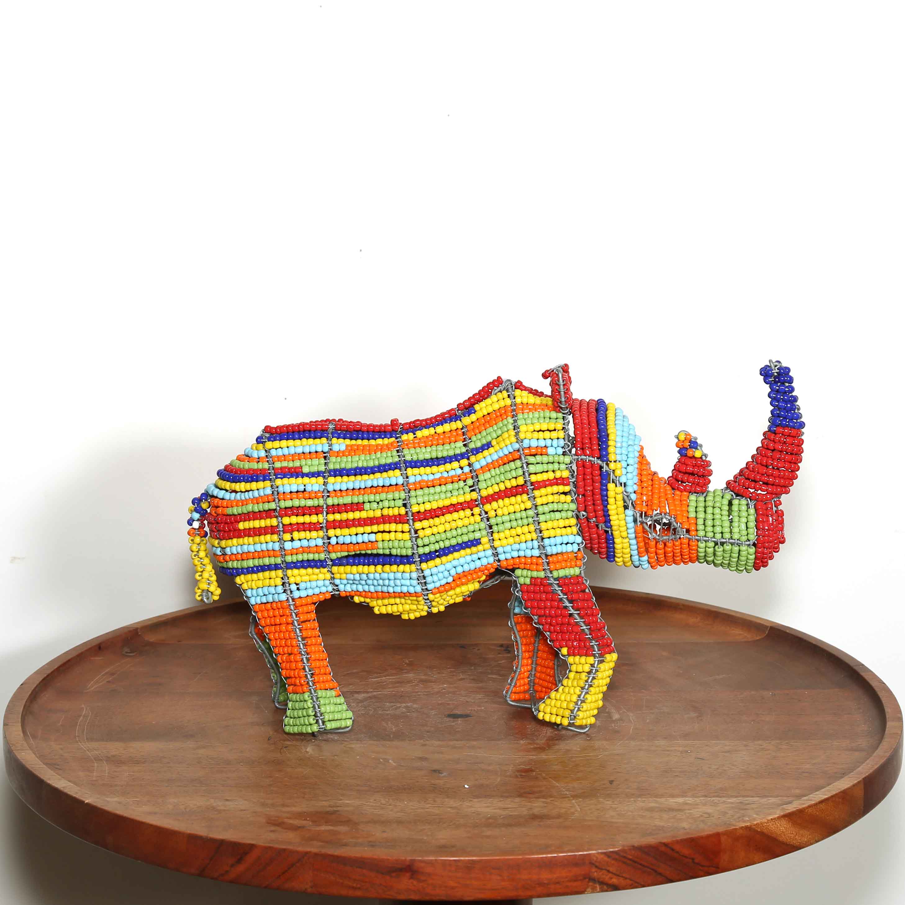 Colorful rhinoceros sculpture made from high quality glass beads on a wooden surface with a white background