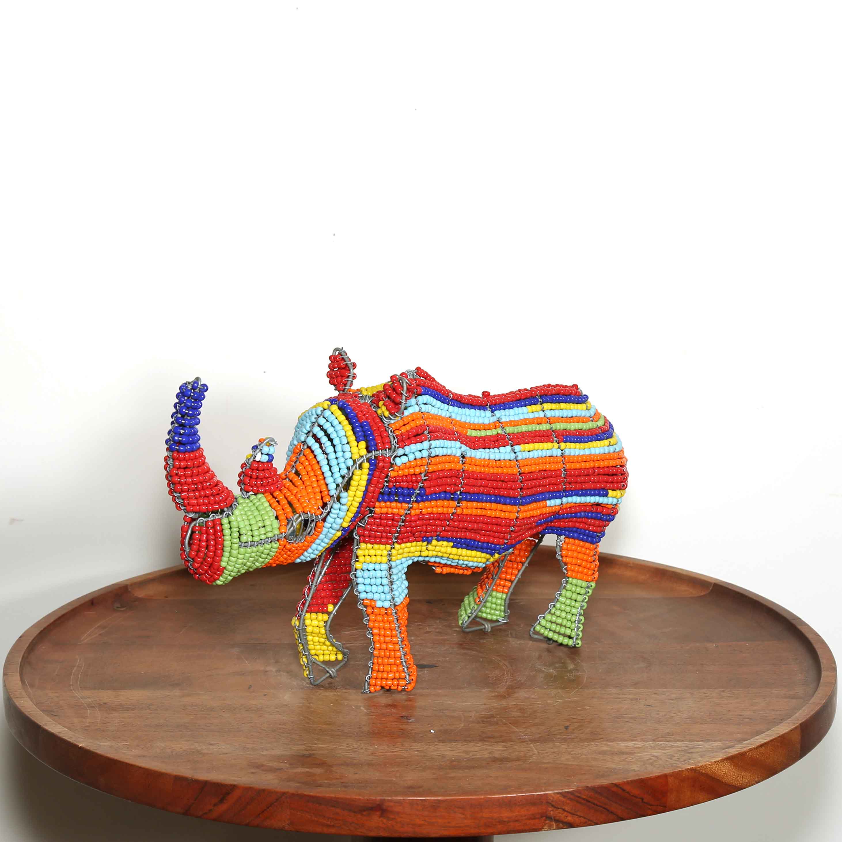 Colorful rhinoceros figurine on a wooden platform with a white background