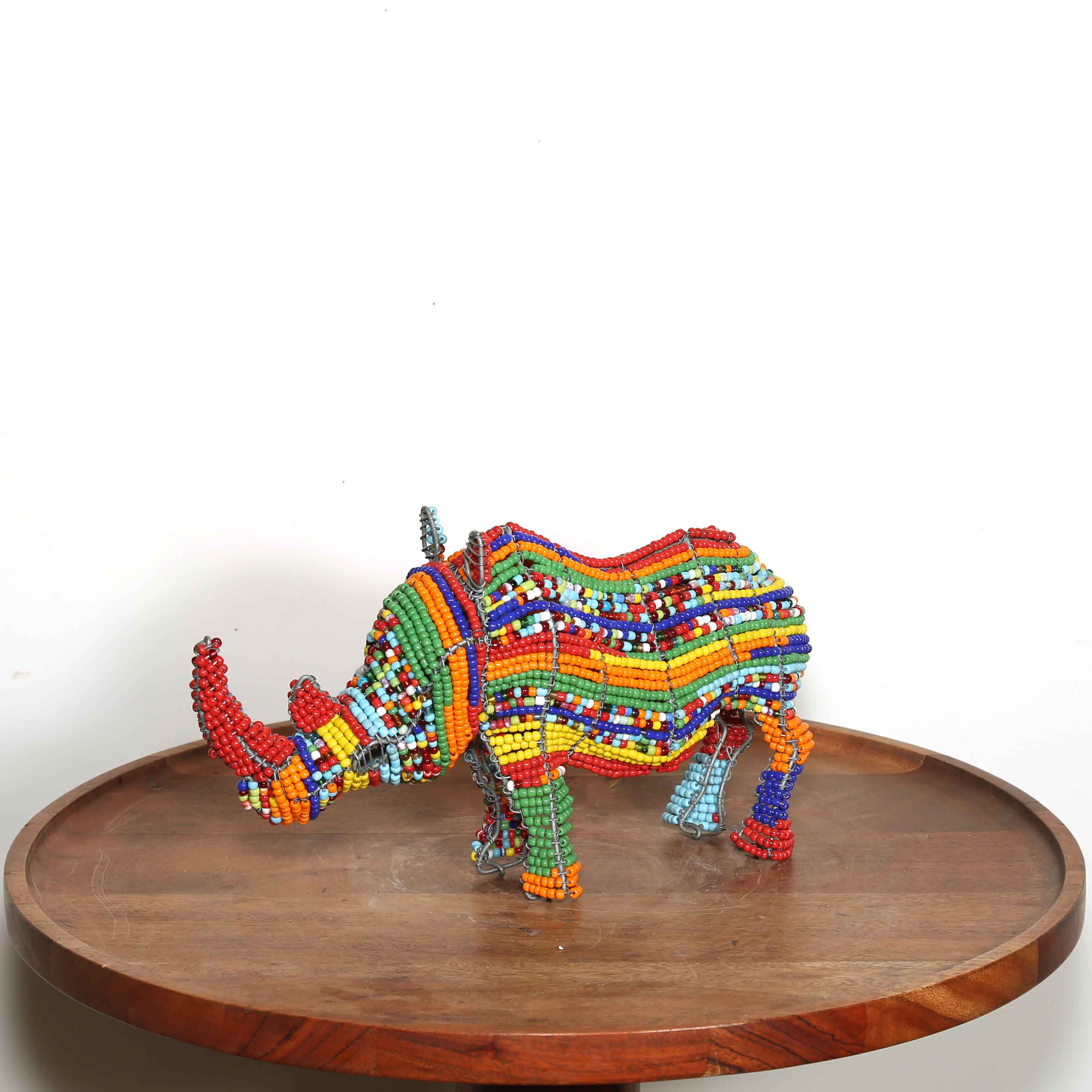 Colorful beaded rhino on a wooden platform with a white background