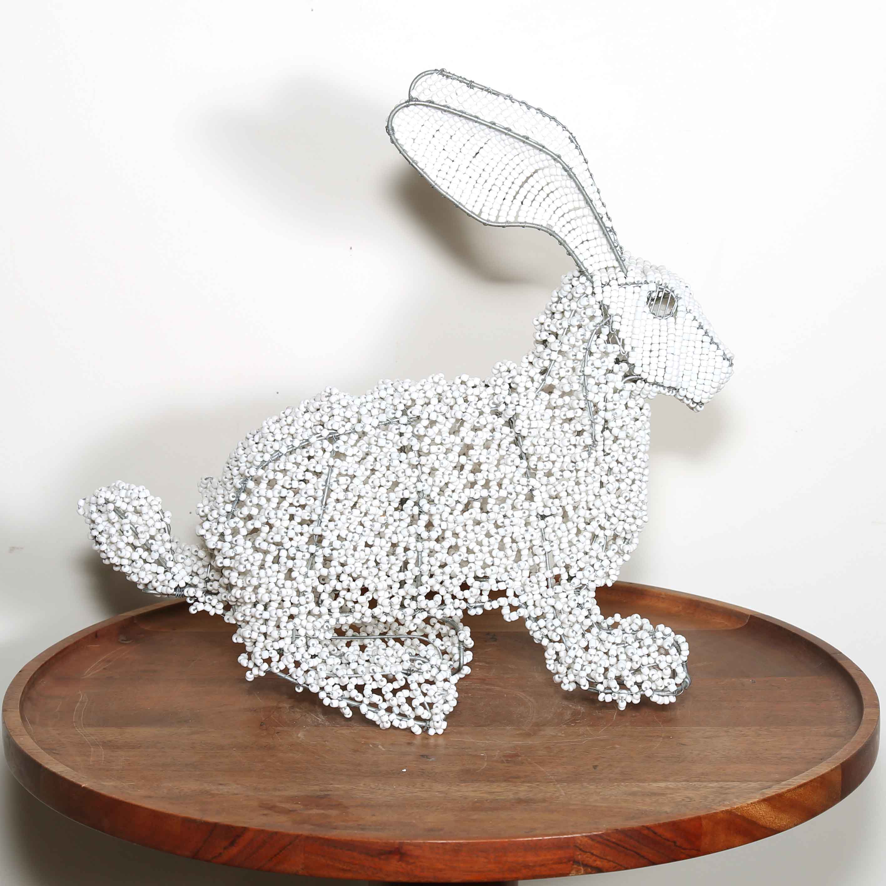 Decorative white rabbit sculpture on a wooden platform against a plain background from Africa