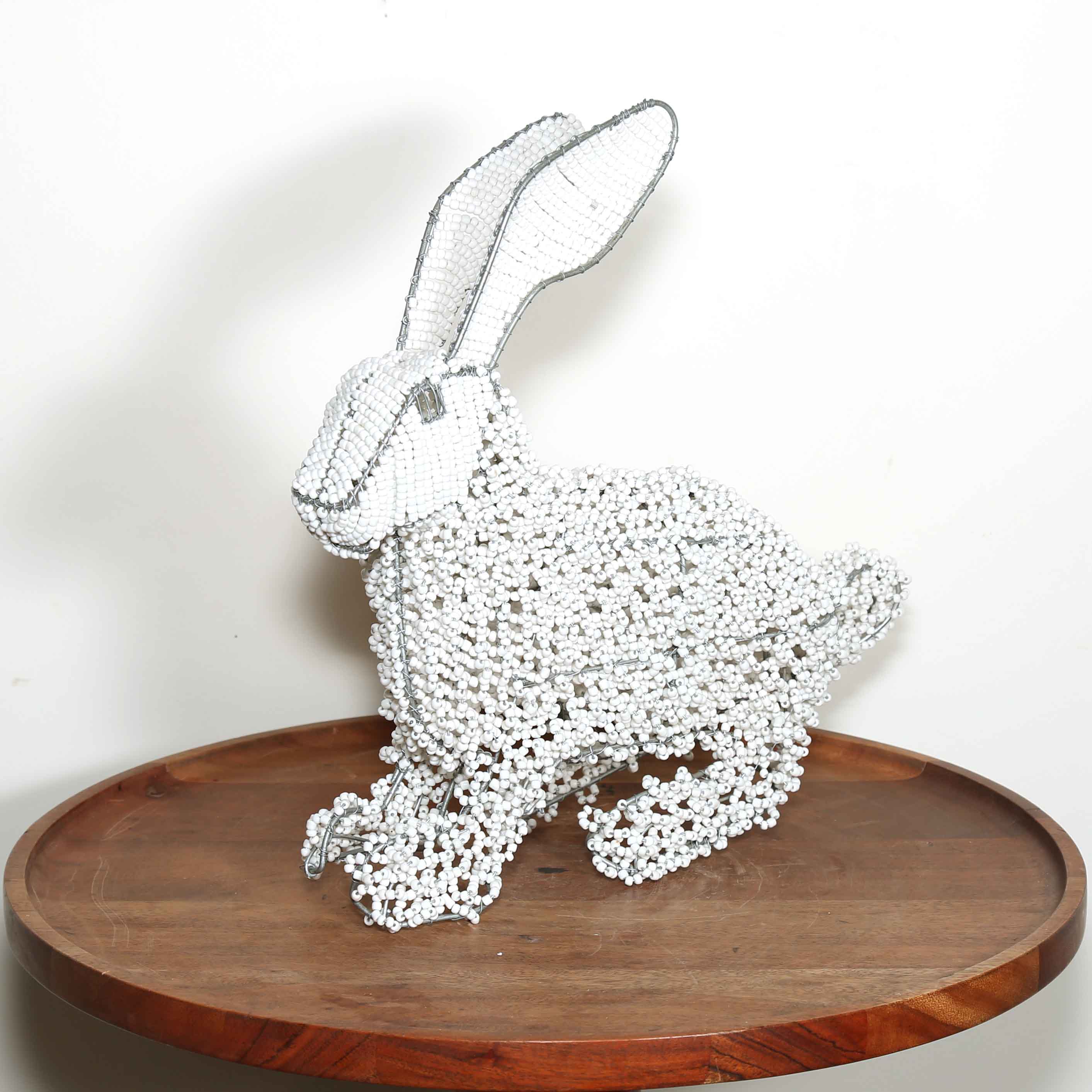 Decorative rabbit sculpture made of white beads on a wooden platform with a white background handmade in South Africa