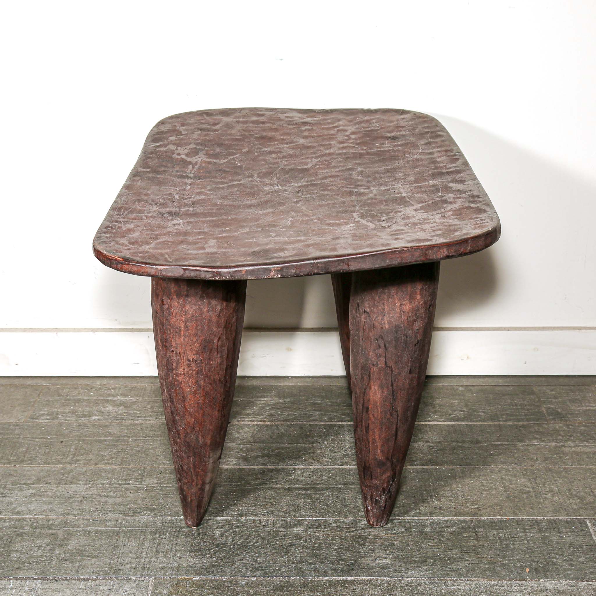 square African wood table with four pointed legs on a wooden floor