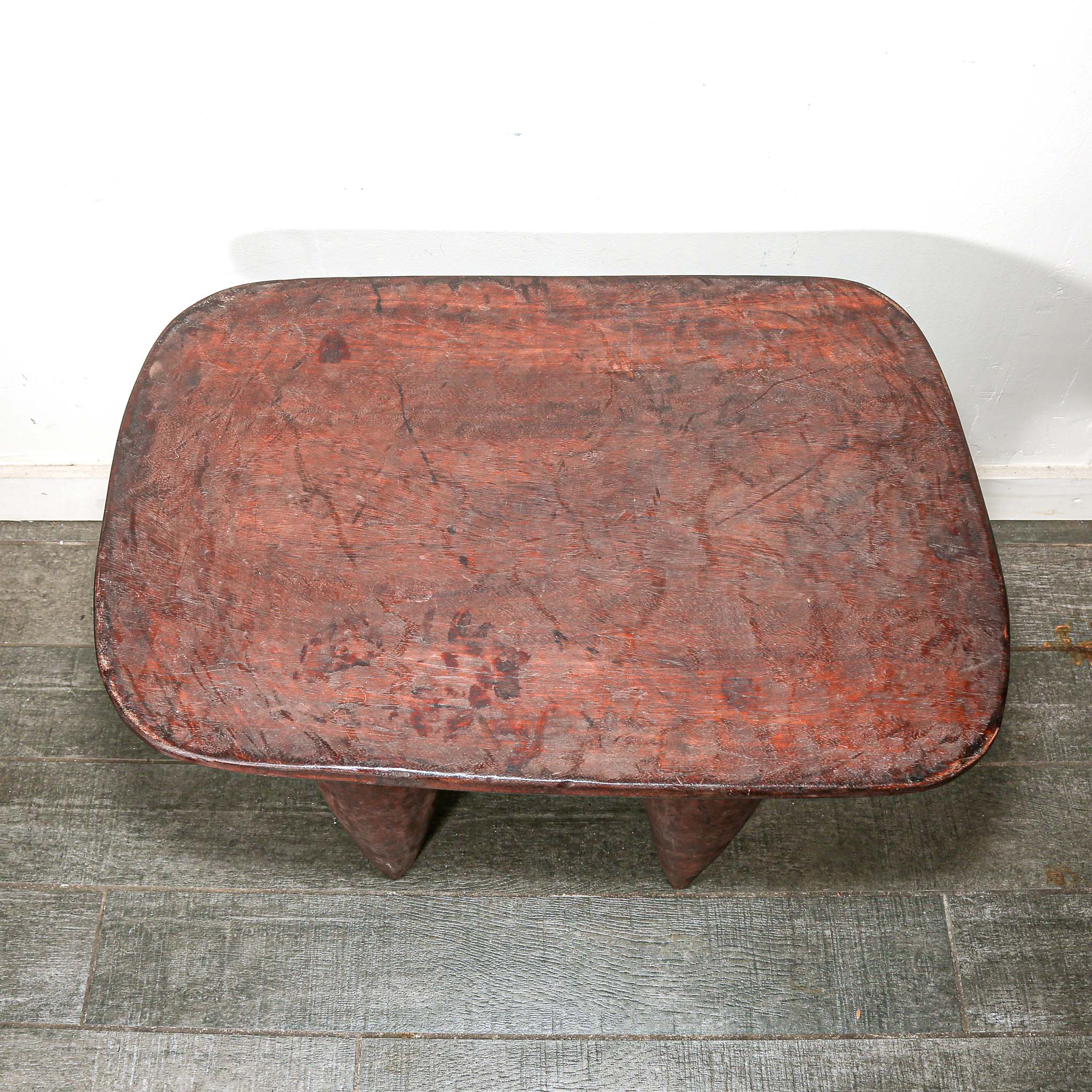 vintage square African wood table with four pointed legs on a wooden floor