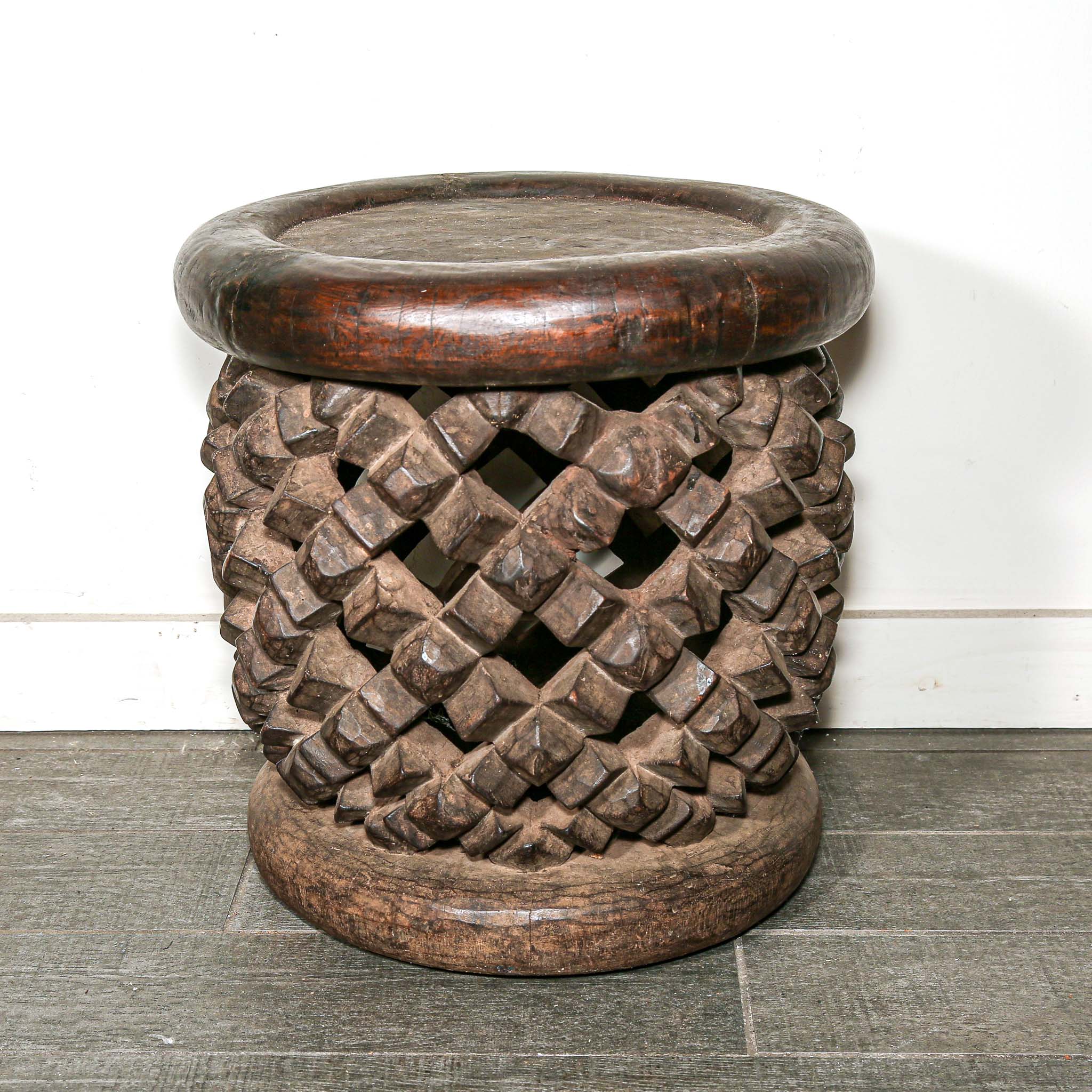 round vintage stool from Africa with a carved woven design on a living room floor