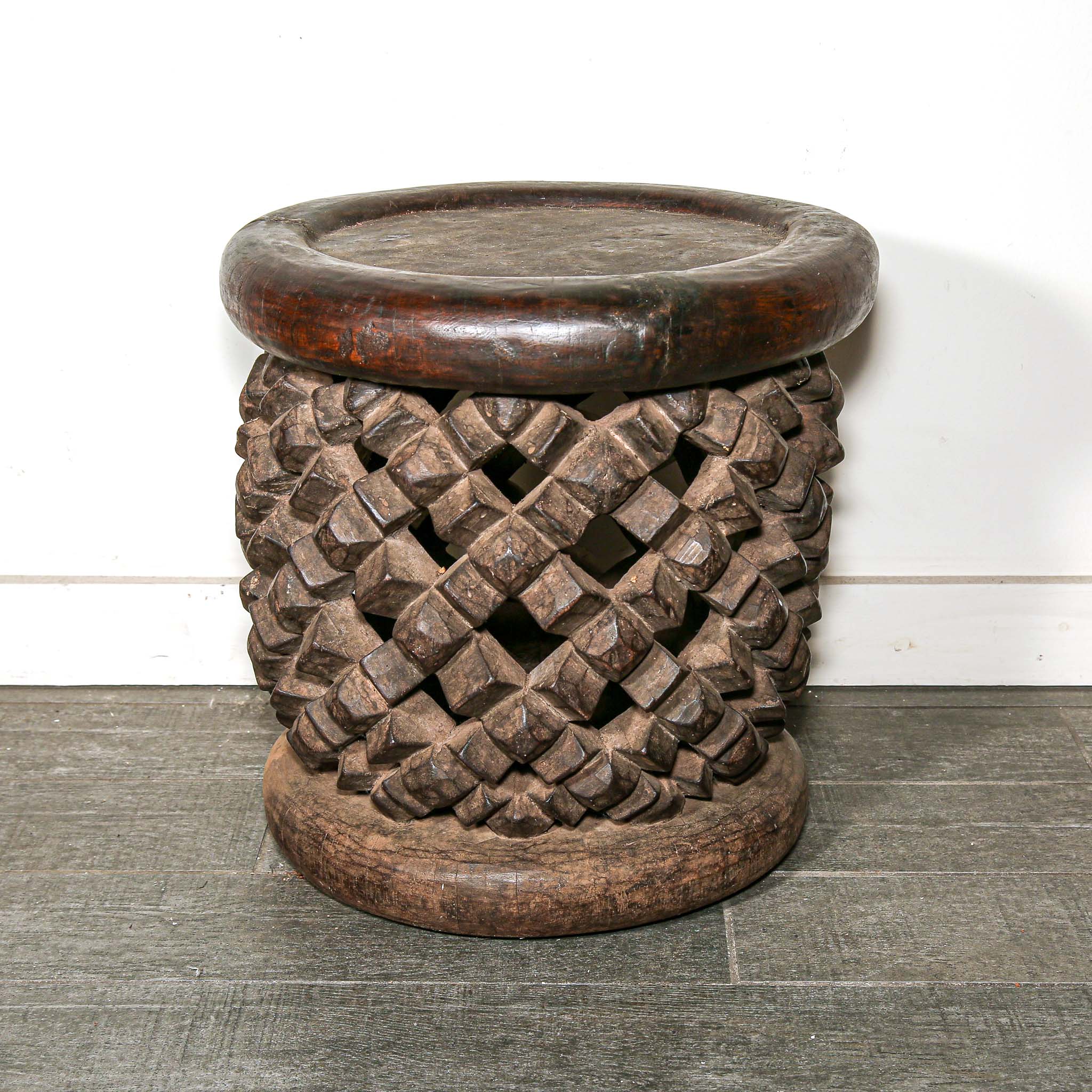 round vintage stool from Africa with a carved woven design on a living room floor