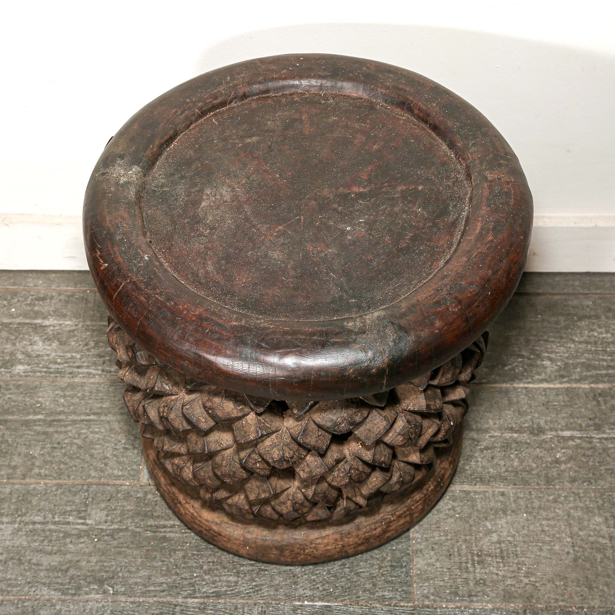 round vintage stool from Africa with a carved woven design on a living room floor