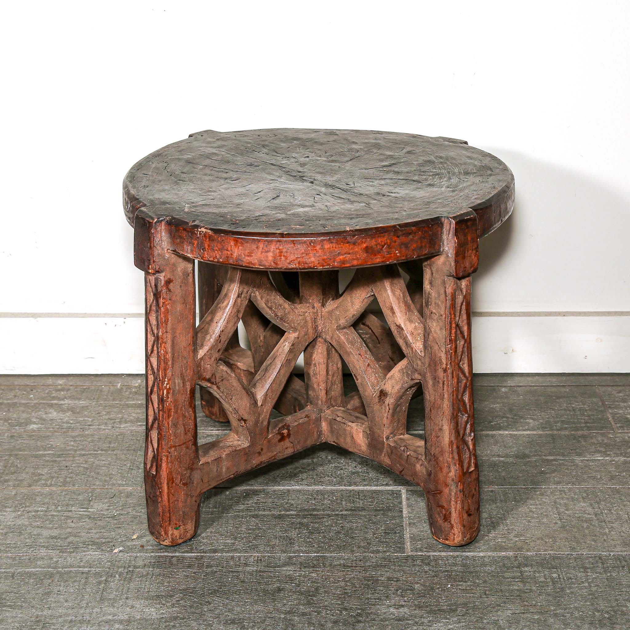 rustic African Round wooden table with a handmade feel on a bedroom floor