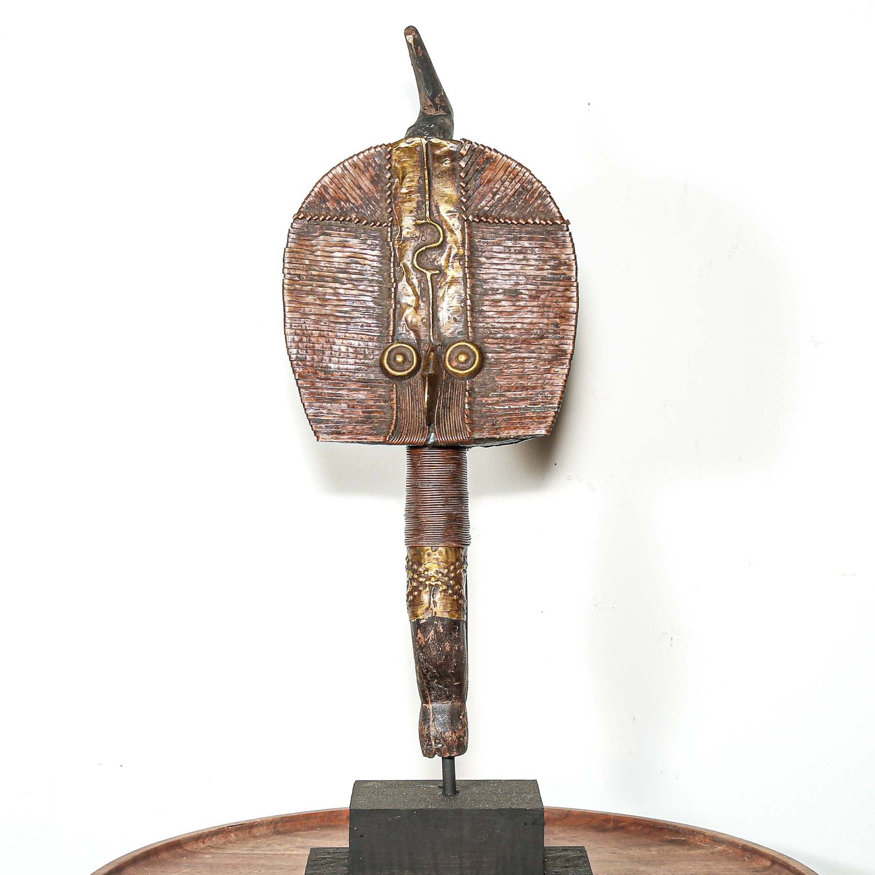 Decorative vintage African art on a stand with a white background