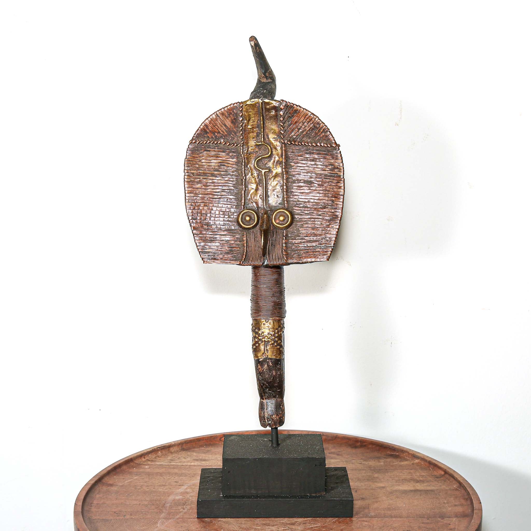 Decorative vintage African art on a stand with a white background