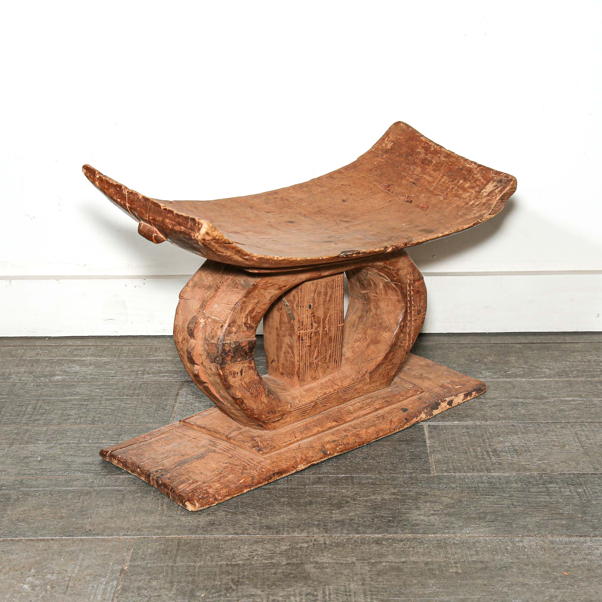 Wooden African table stool with curved top and base on a wooden floor used as bedroom African furniture 